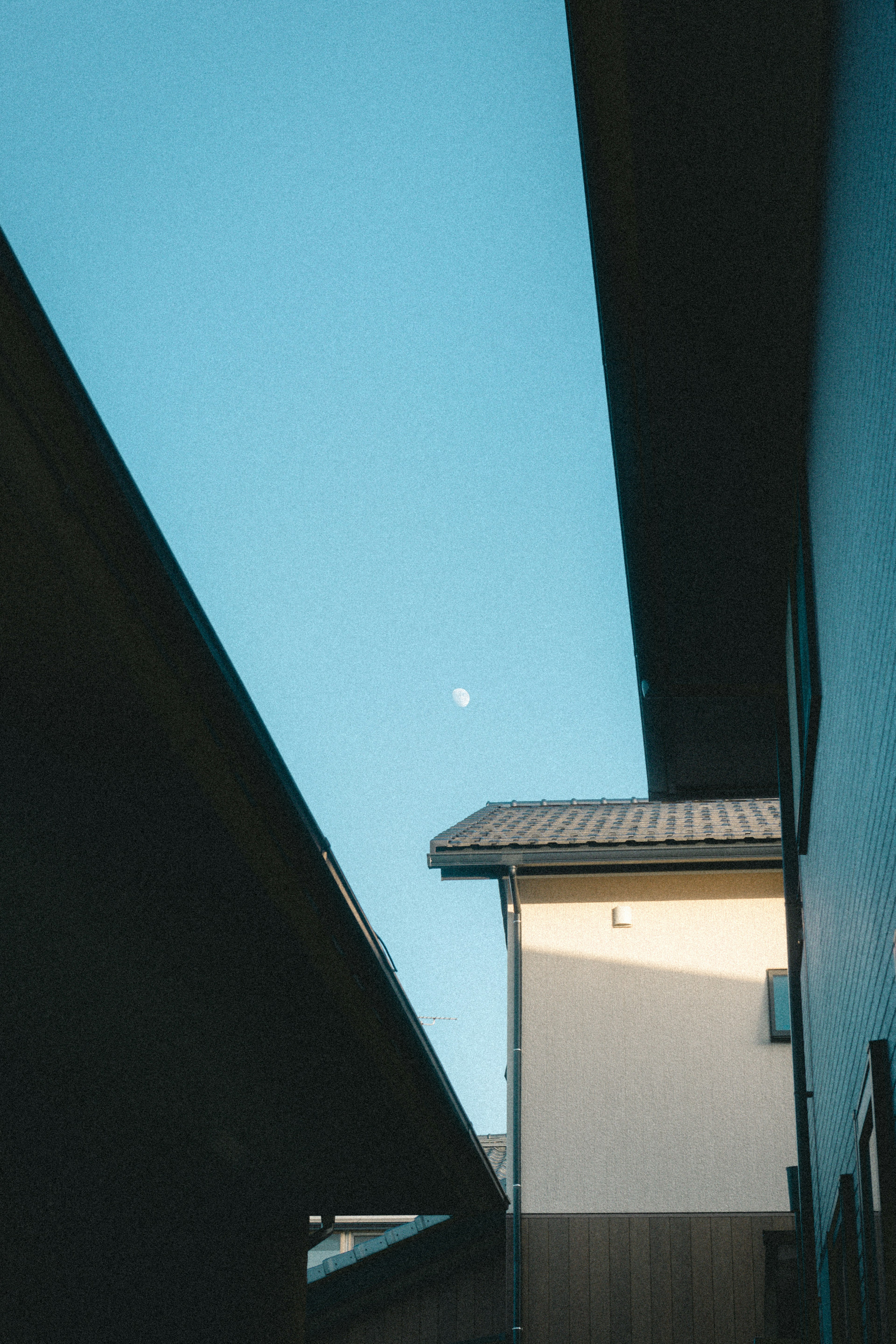 Vista tra gli edifici con cielo blu e luna