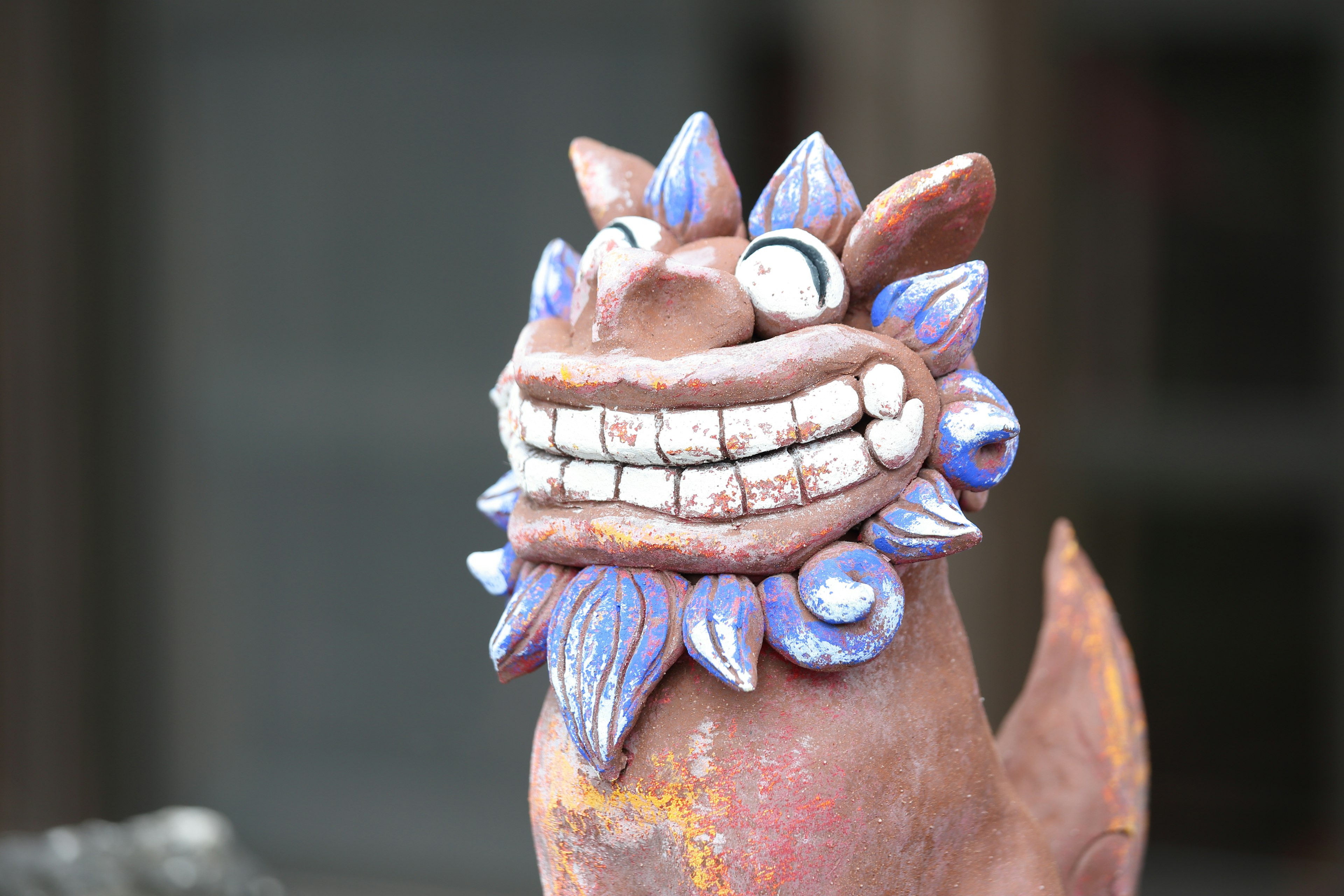 Unique ceramic lion statue with a smiling expression and blue decorations