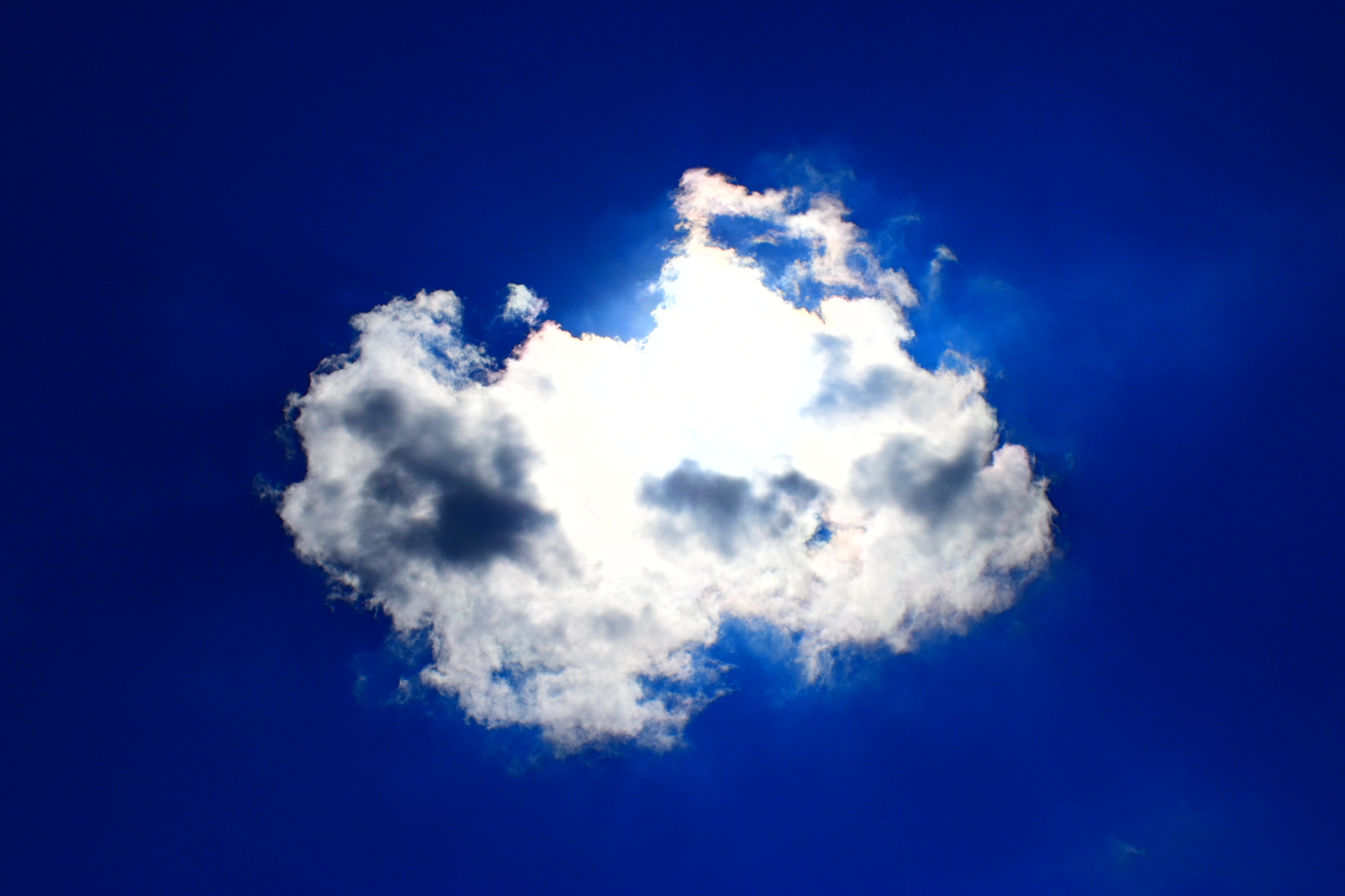 Weißer Wolke, die von Sonnenlicht gegen einen blauen Himmel beleuchtet wird