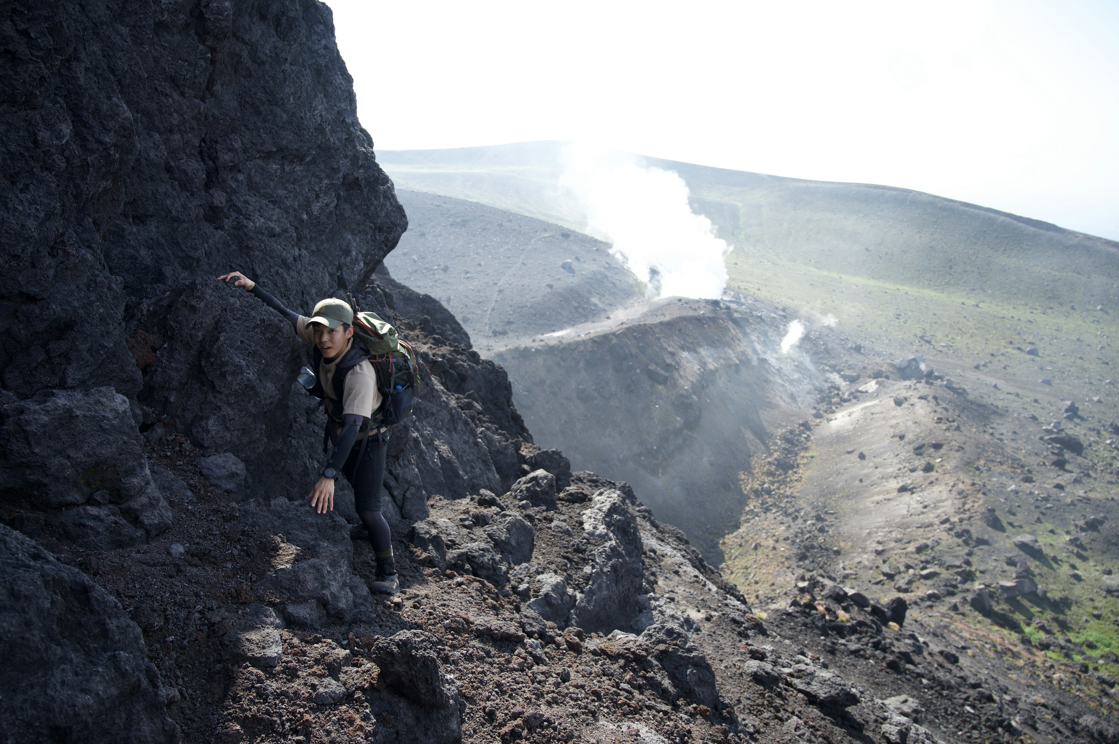 攀爬火山坡的徒步旅行者，背景中冒烟的火口