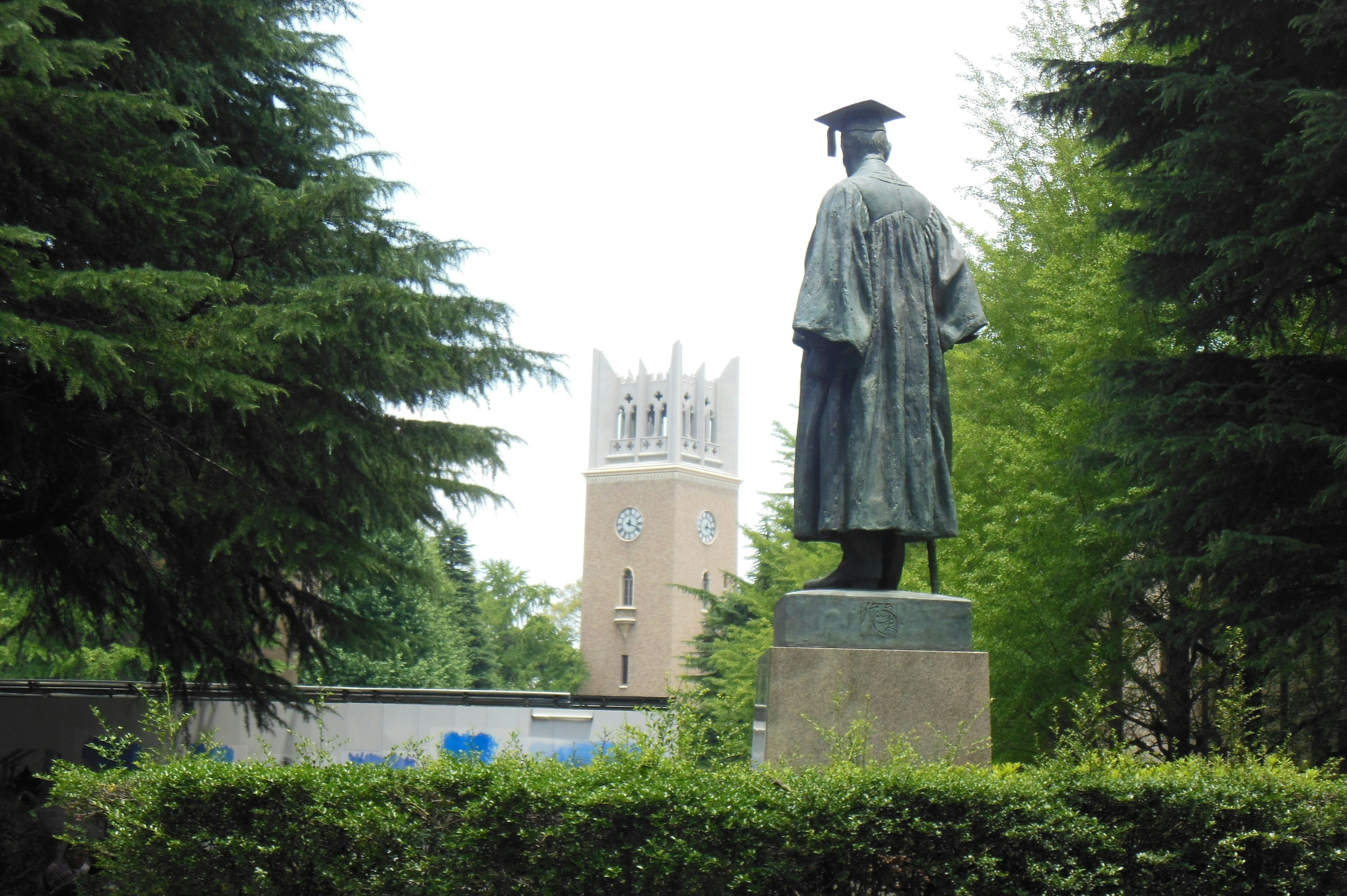 Estatua de un graduado con una torre al fondo