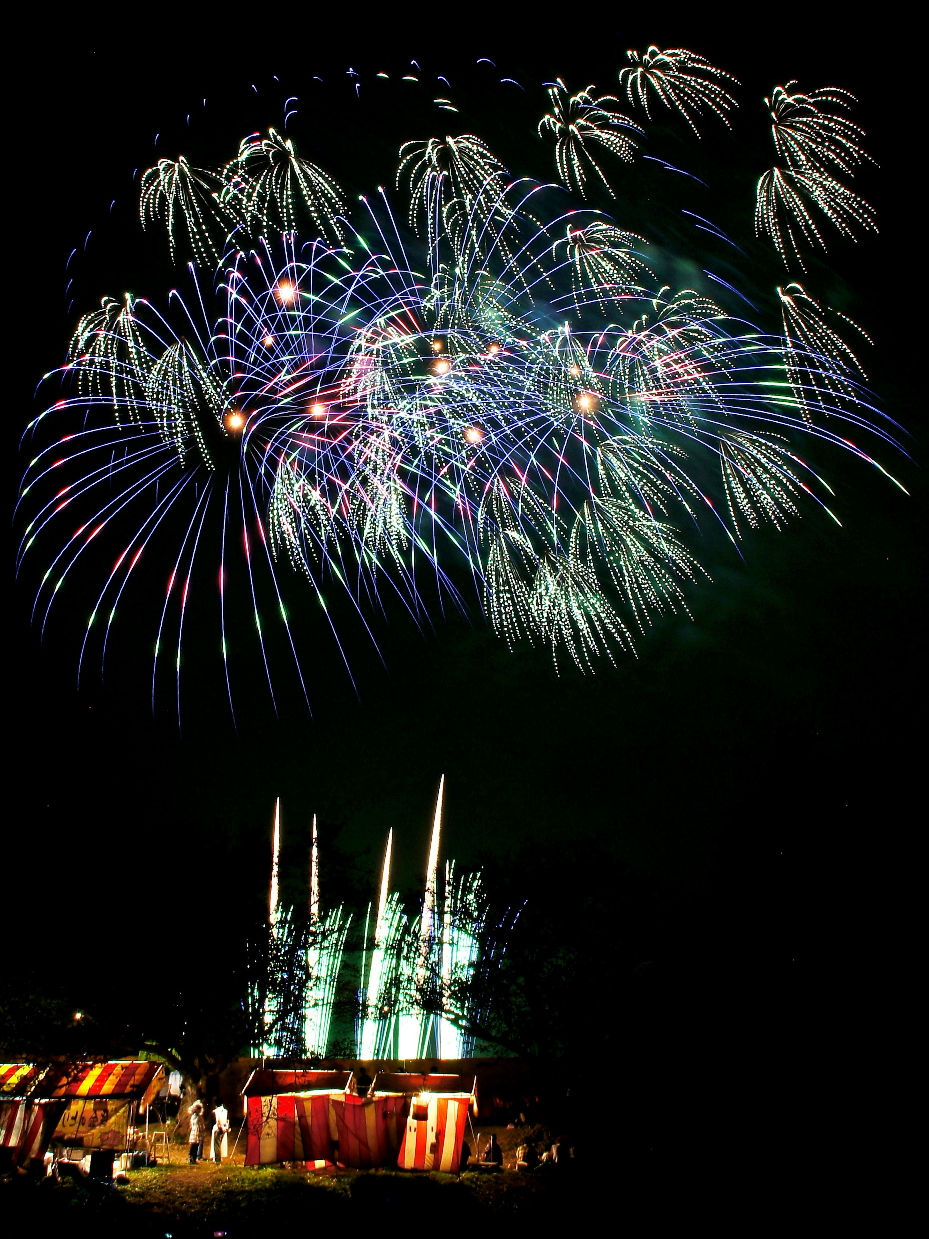 Fuegos artificiales coloridos iluminando el cielo nocturno sobre un parque de diversiones