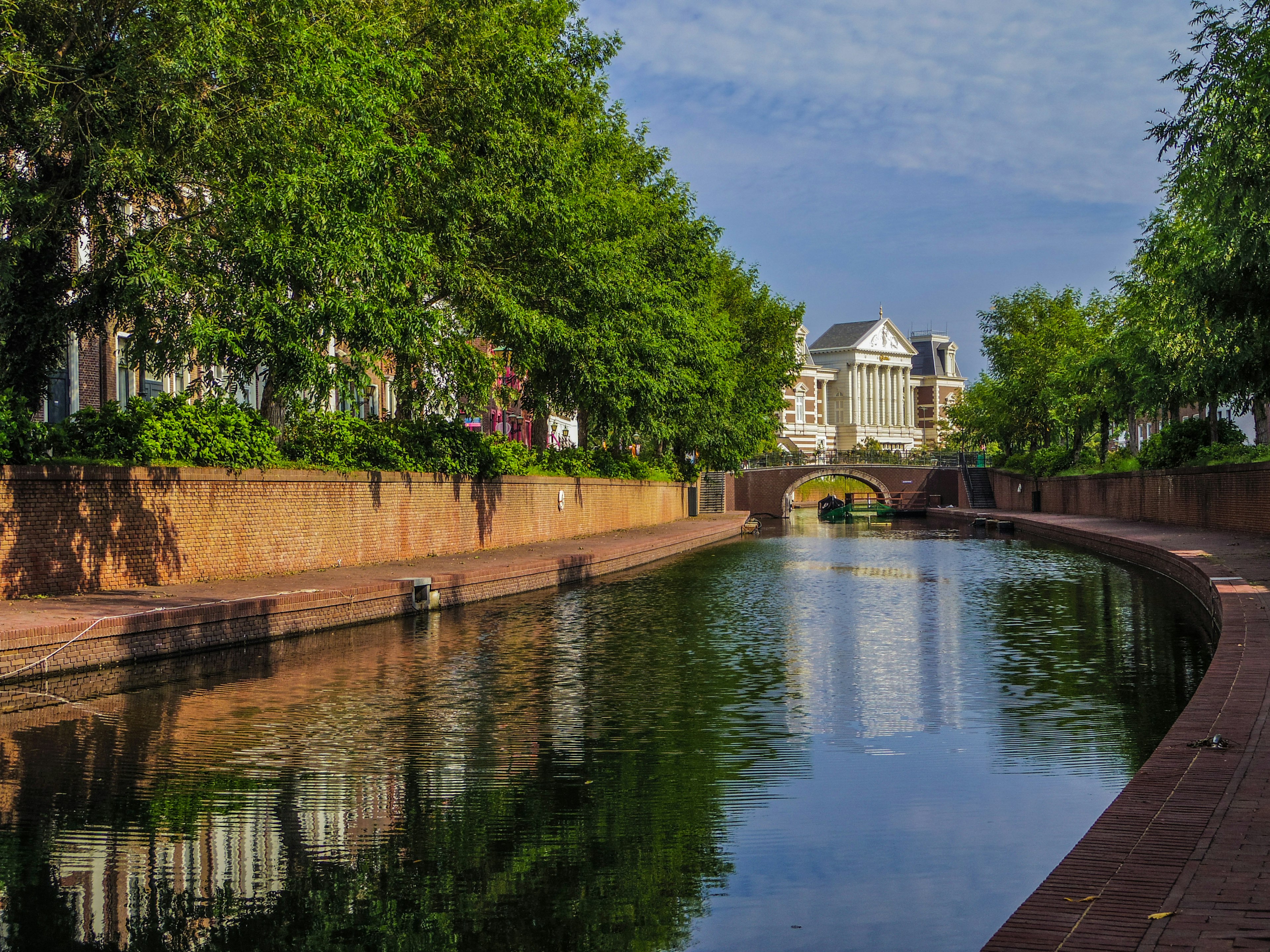 Vista escénica de un canal con vegetación exuberante y edificios históricos