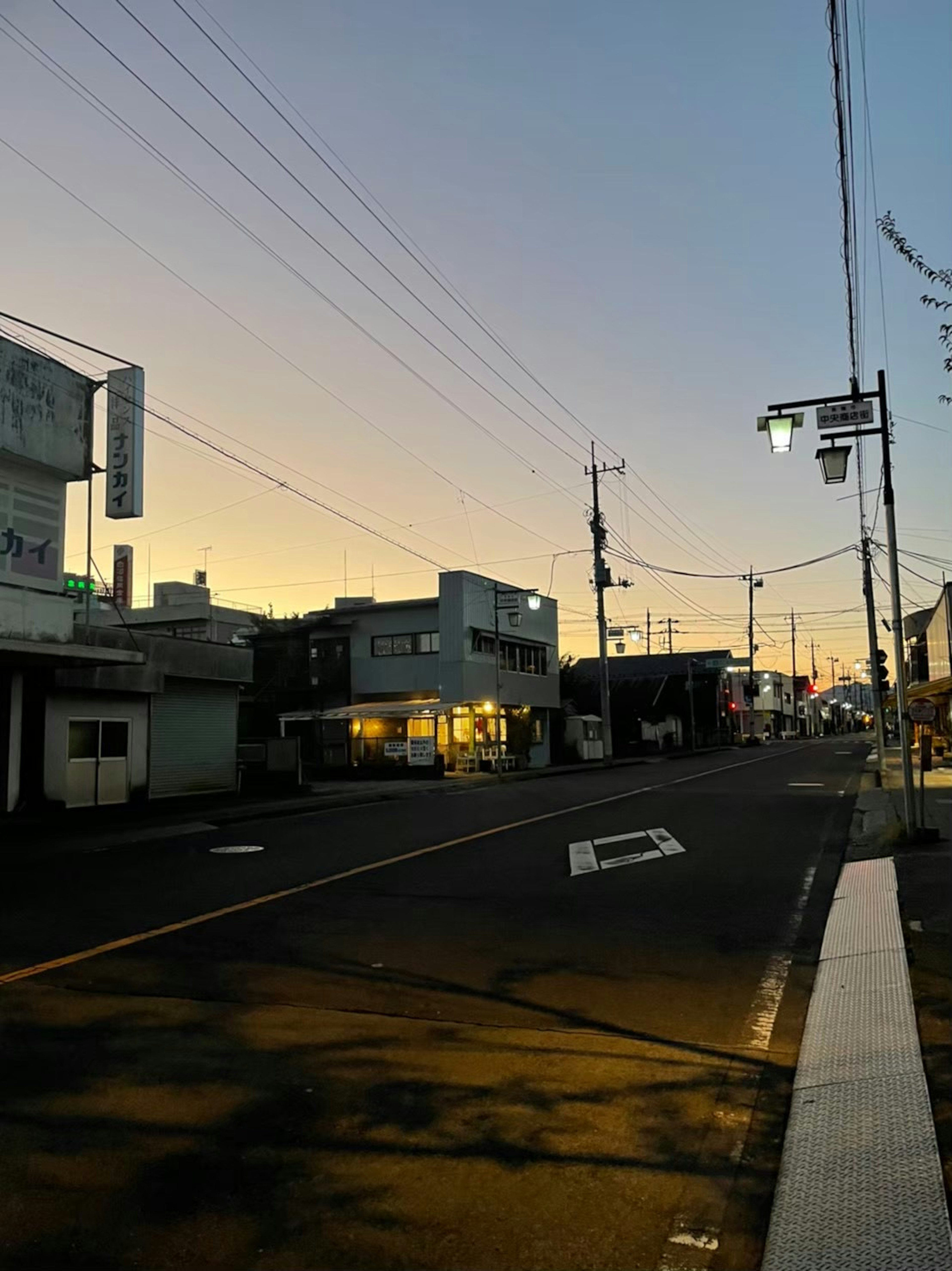 Escena de calle tranquila al atardecer con edificios y líneas eléctricas