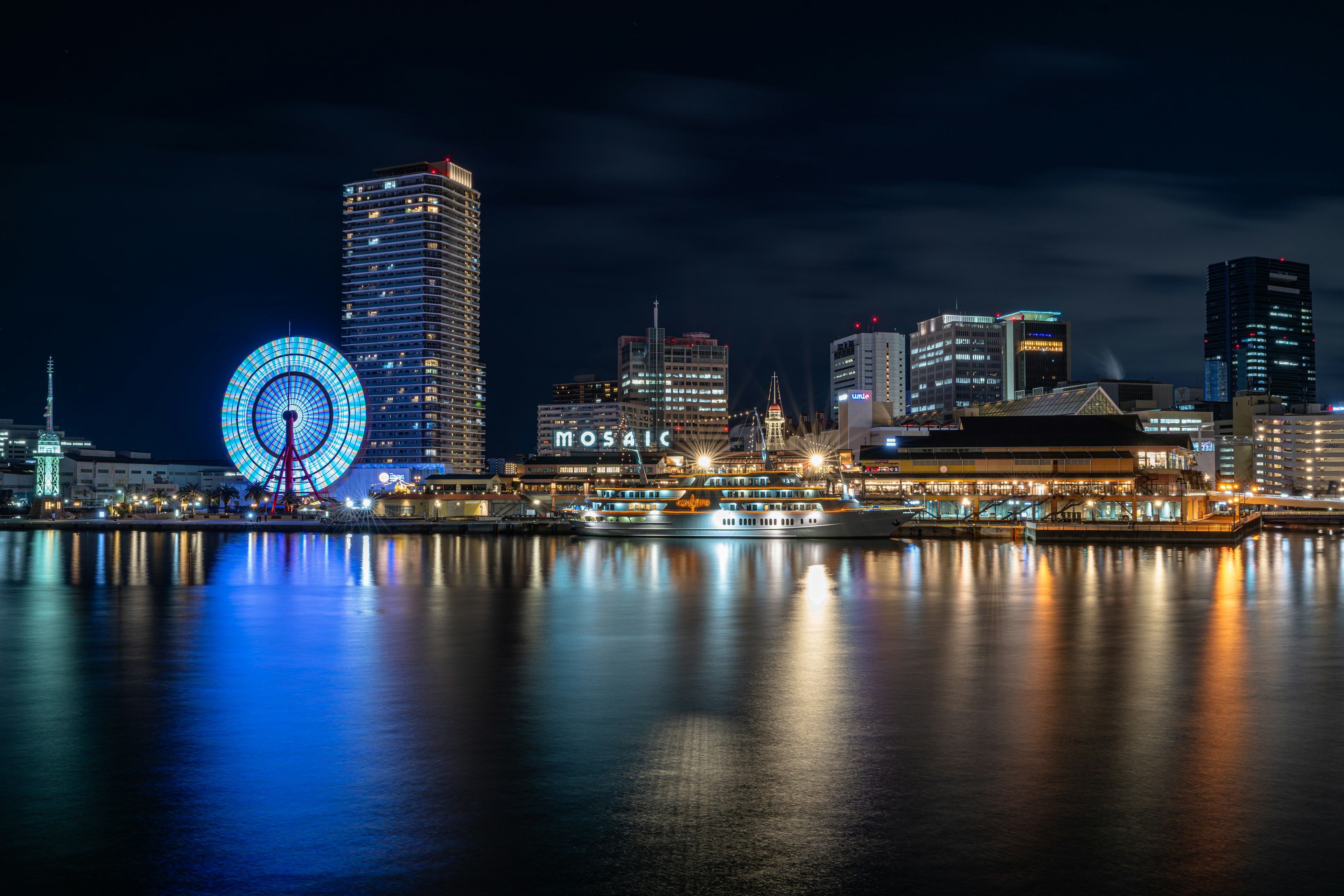 Pemandangan malam yang indah di Pelabuhan Yokohama dengan bianglala dan gedung pencakar langit yang diterangi