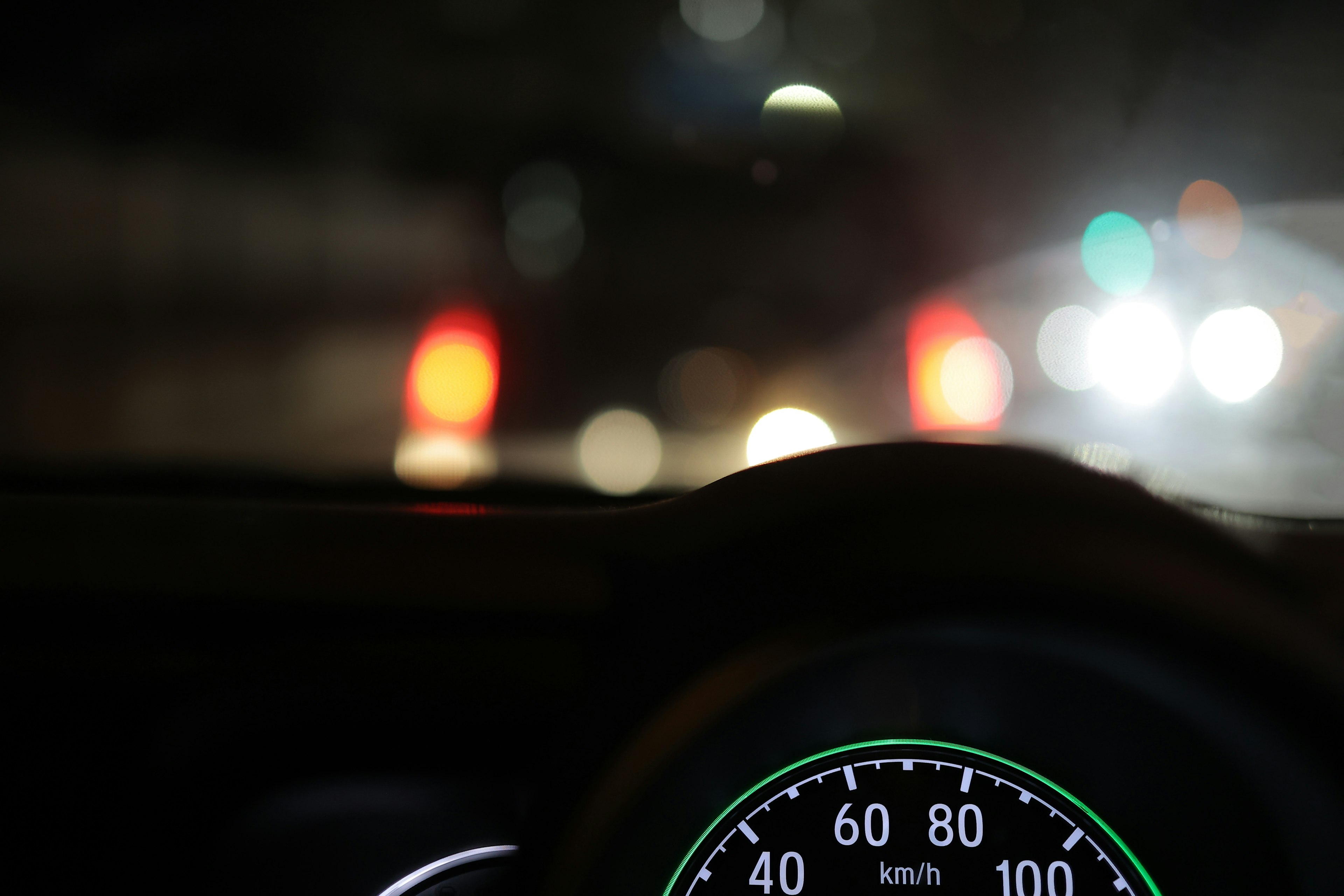 Close-up dasbor mobil dan speedometer saat berkendara di malam hari