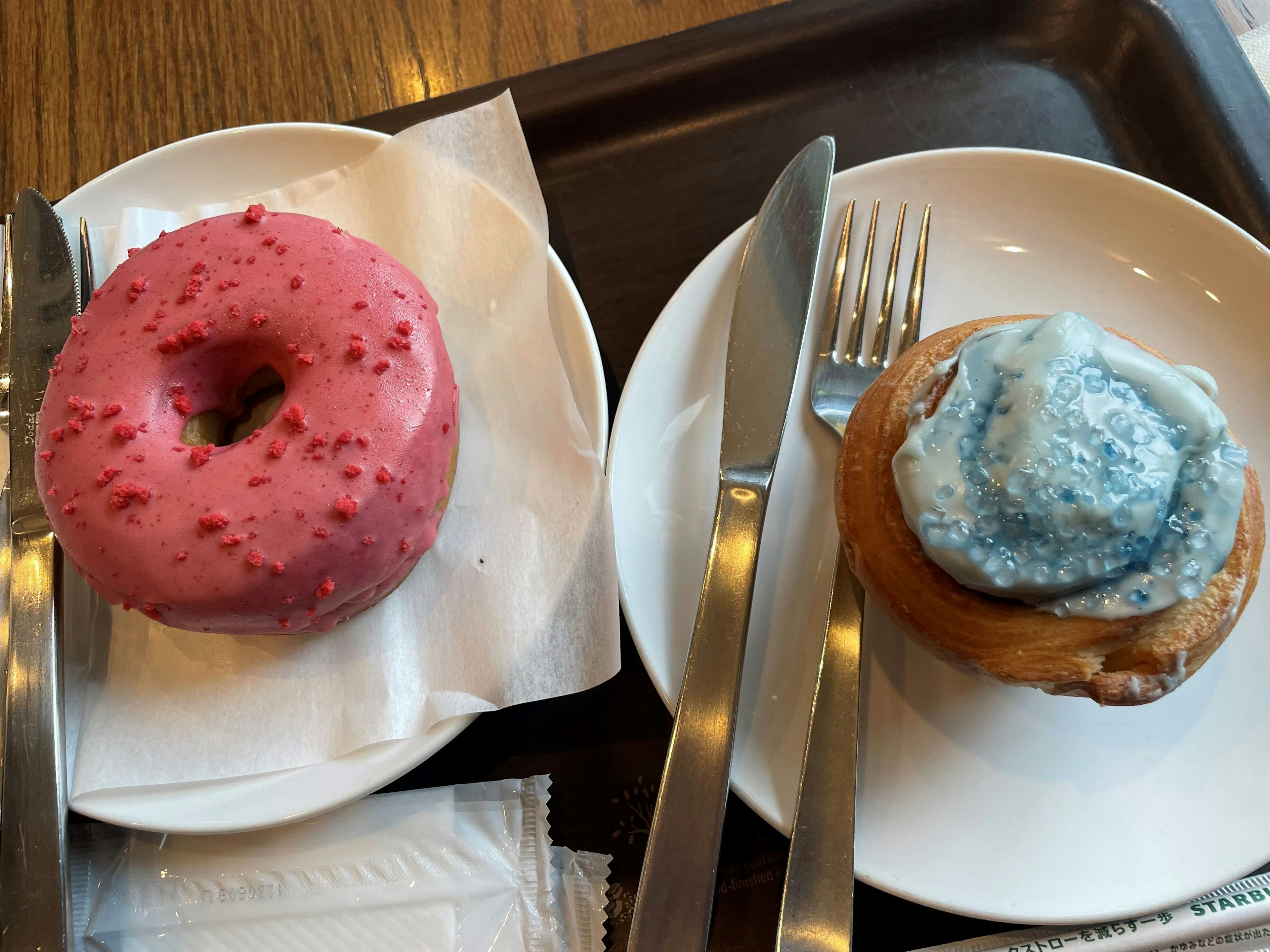 Donut rosa con chispas y rollo de canela con glaseado azul en platos blancos