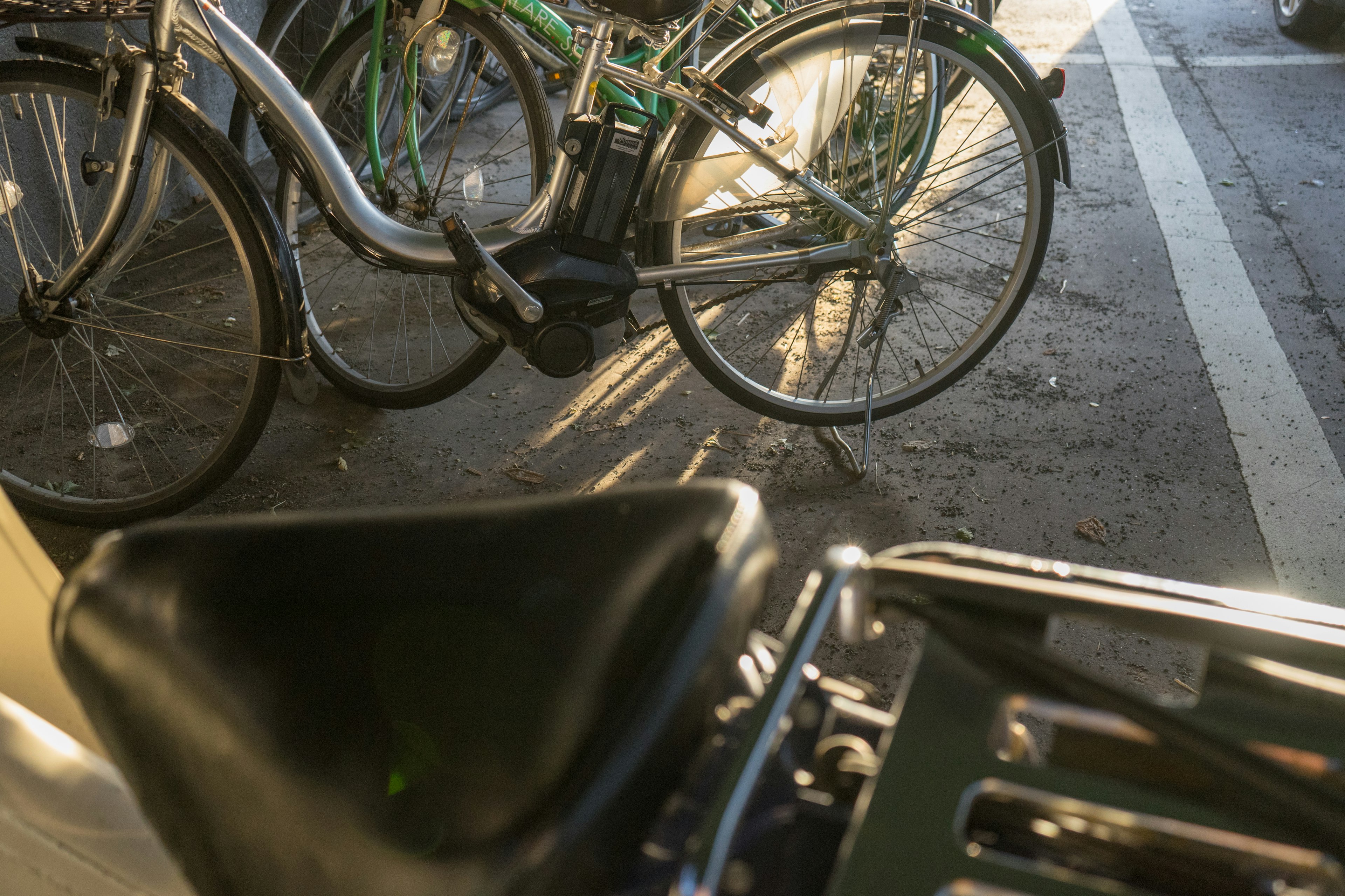 Schwarzer Fahrrad-Sattel mit mehreren Fahrrädern im Hintergrund