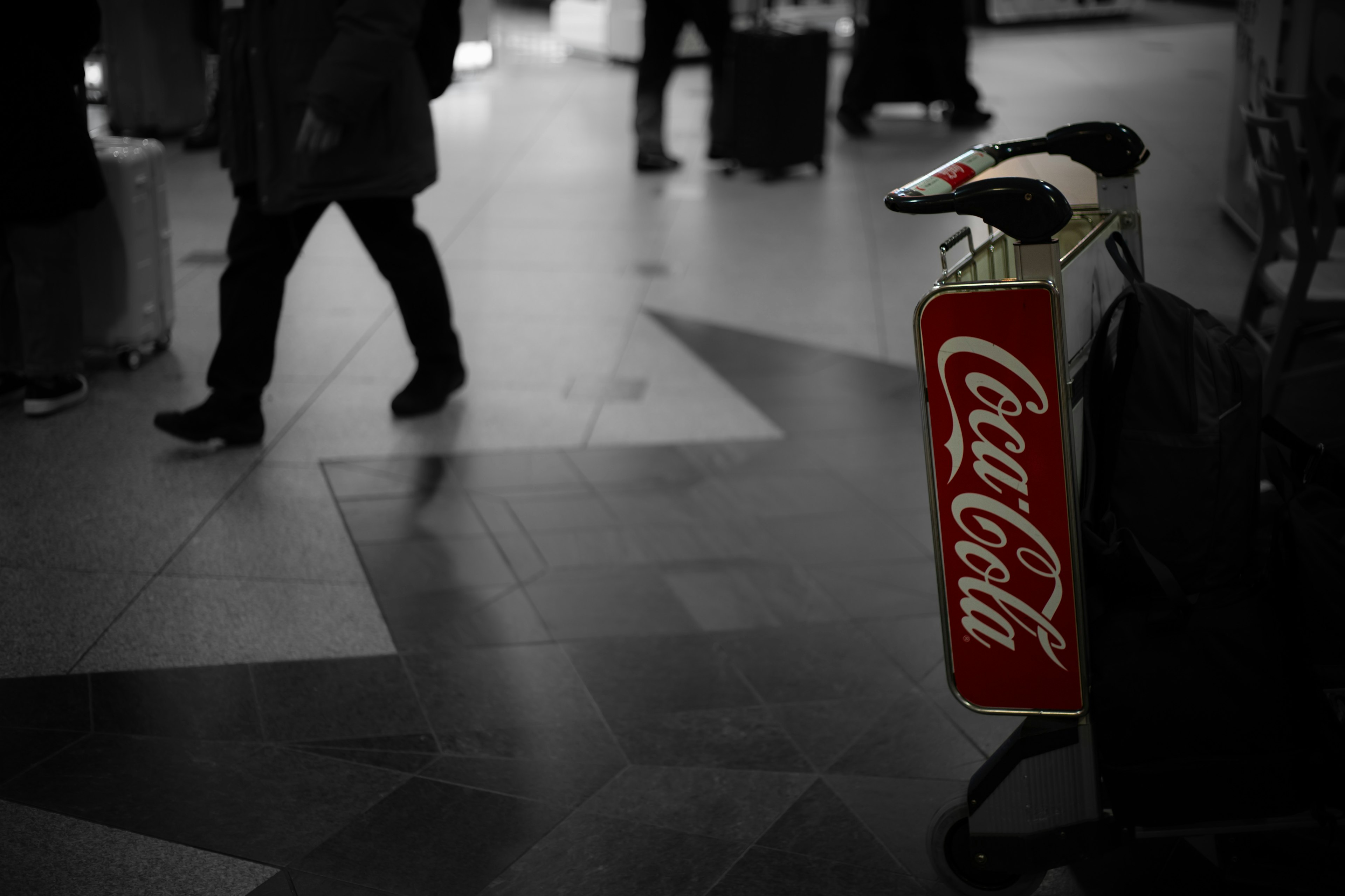 Xe đẩy có biển Coca-Cola và người đi bộ ở phía sau