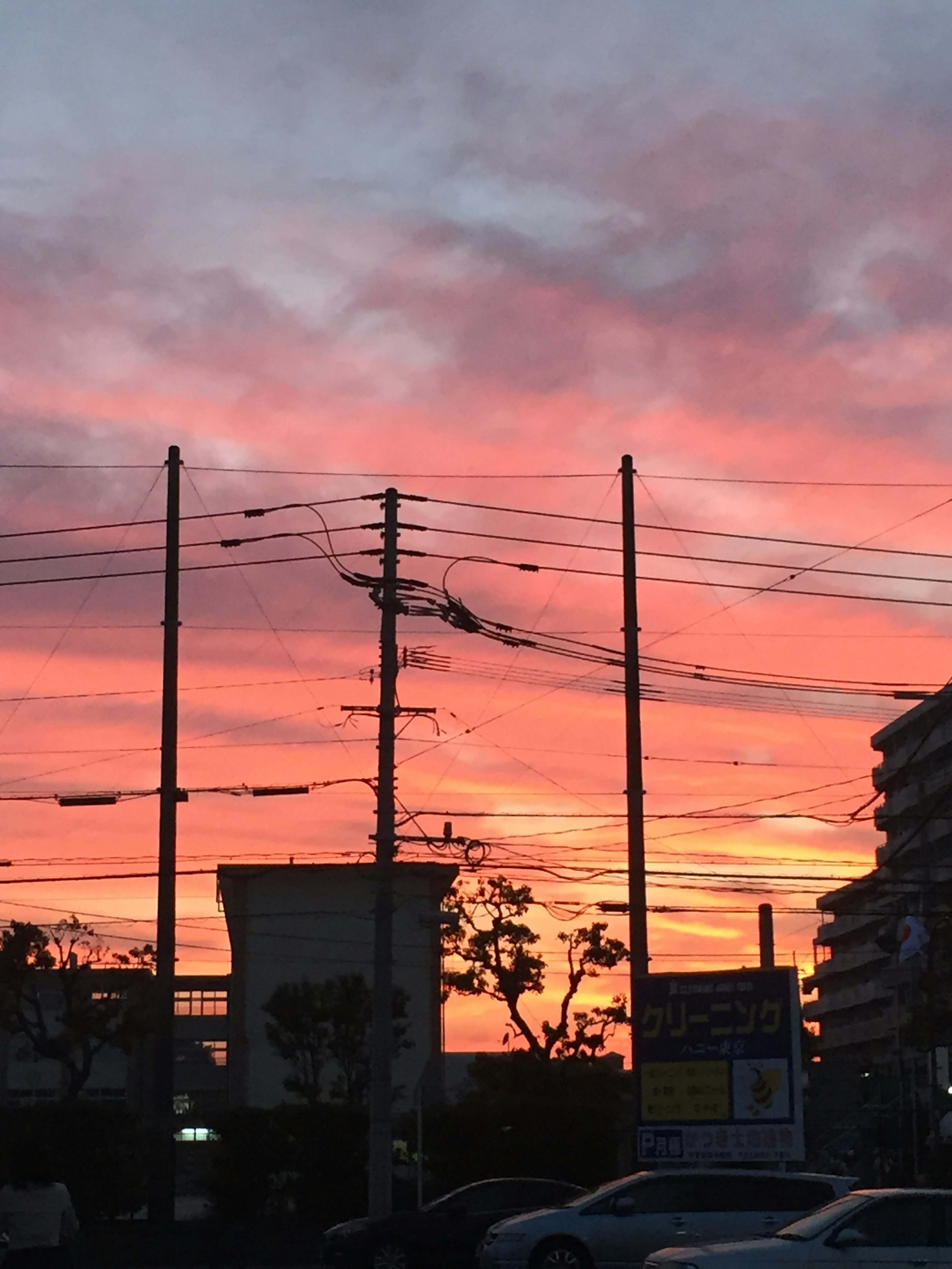 Silhouette of power lines and buildings against a vibrant sunset sky