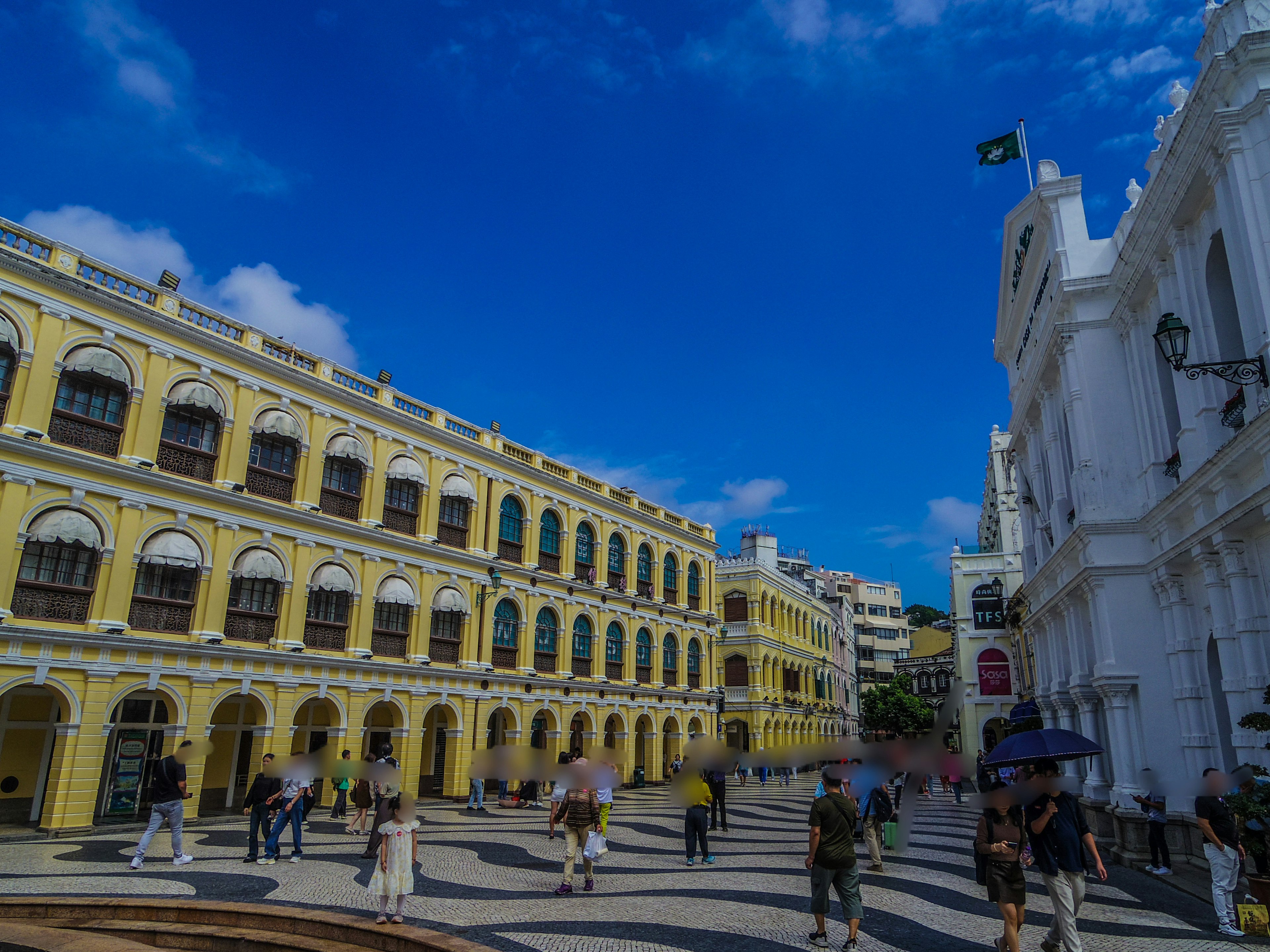 Rues animées de Macao sous un ciel bleu avec des bâtiments jaunes et blancs