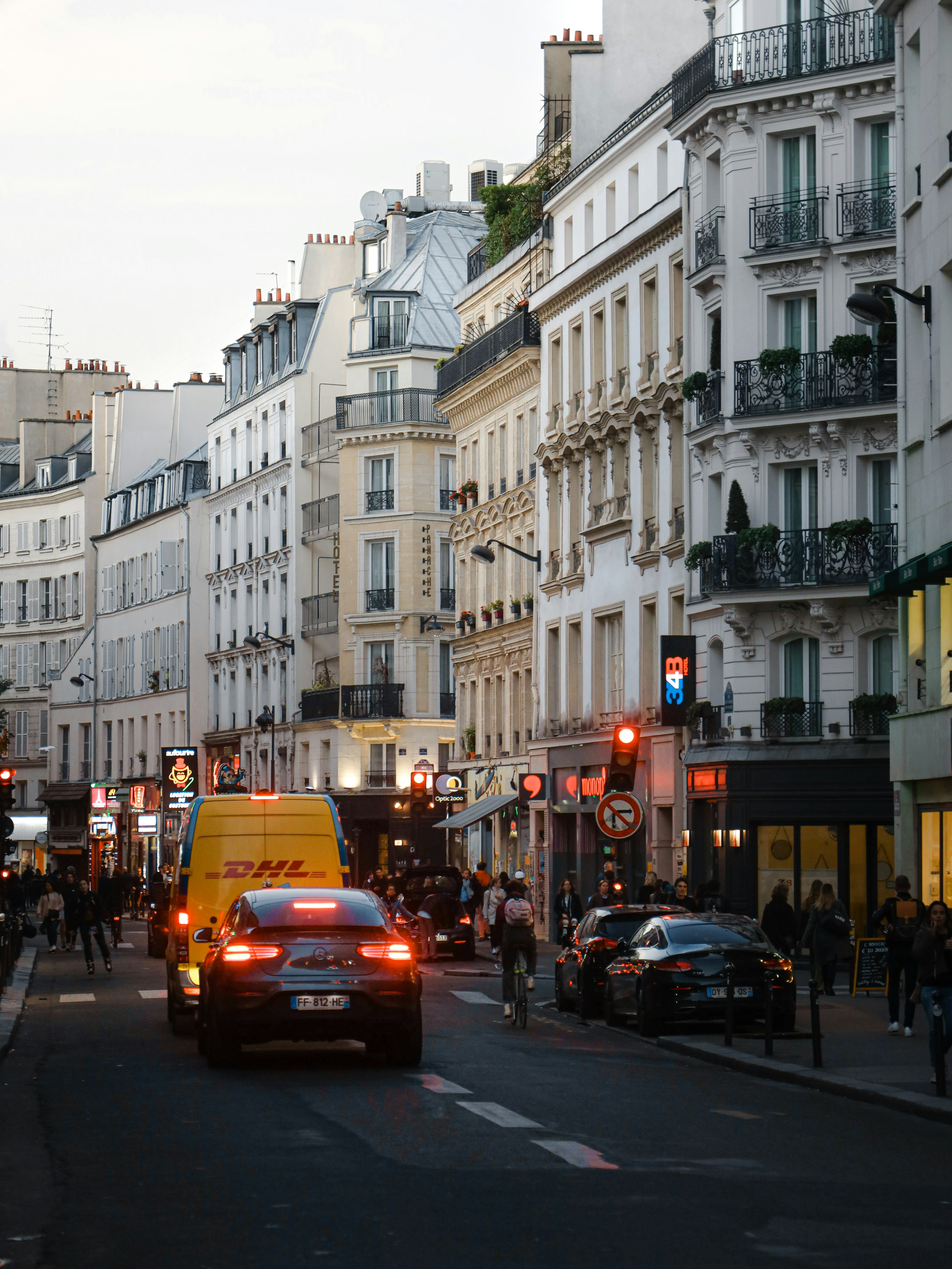 Bustling street scene in Paris at dusk with cars and pedestrians