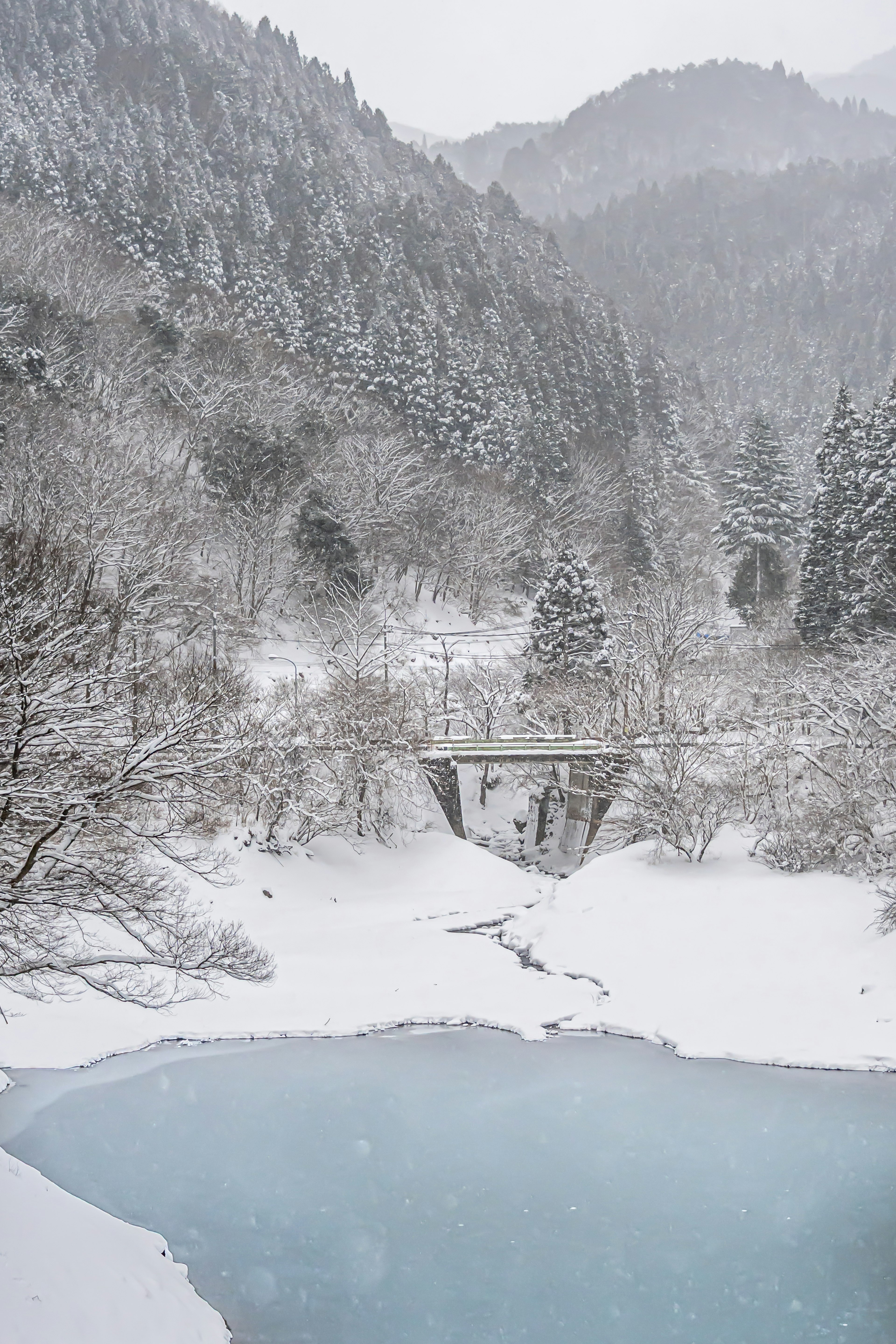 雪覆蓋的山脈與冰凍湖泊上的橋