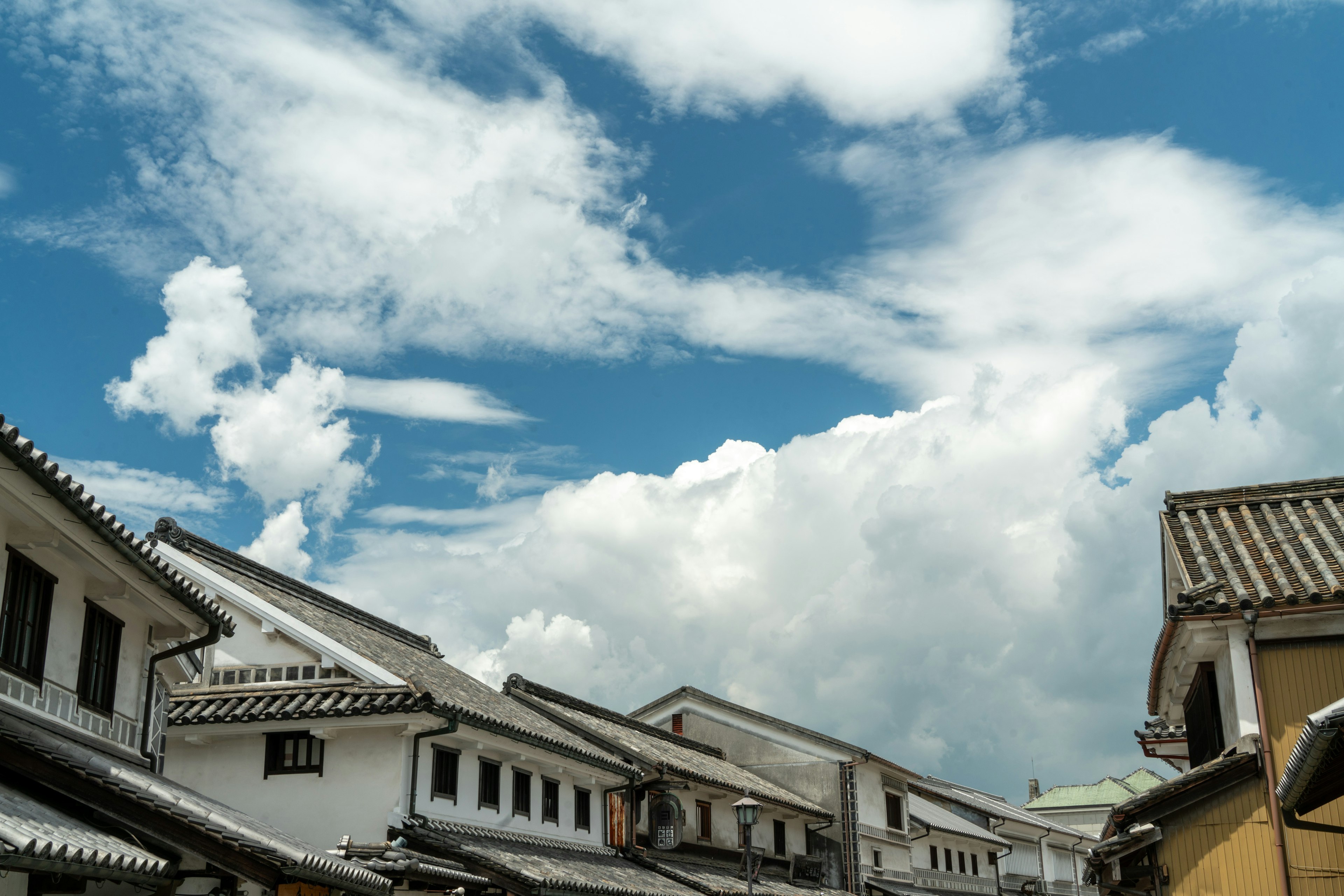 Bâtiments traditionnels alignés sous un ciel bleu avec des nuages blancs