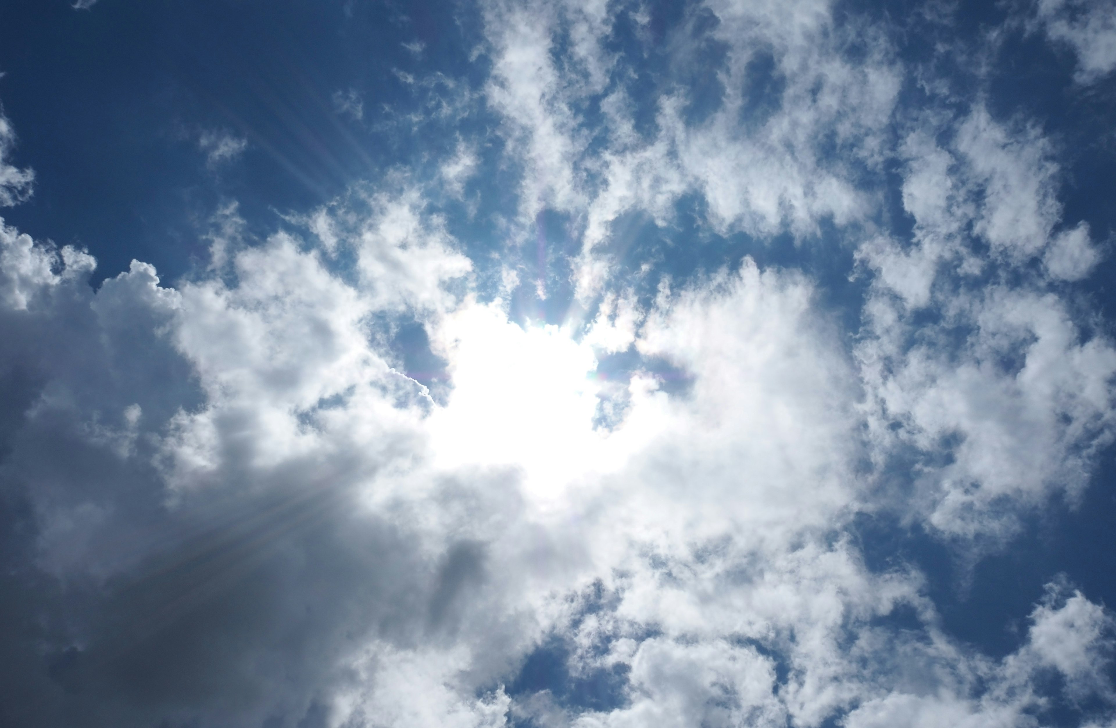 Sonnenlicht bricht durch die Wolken in einem blauen Himmel