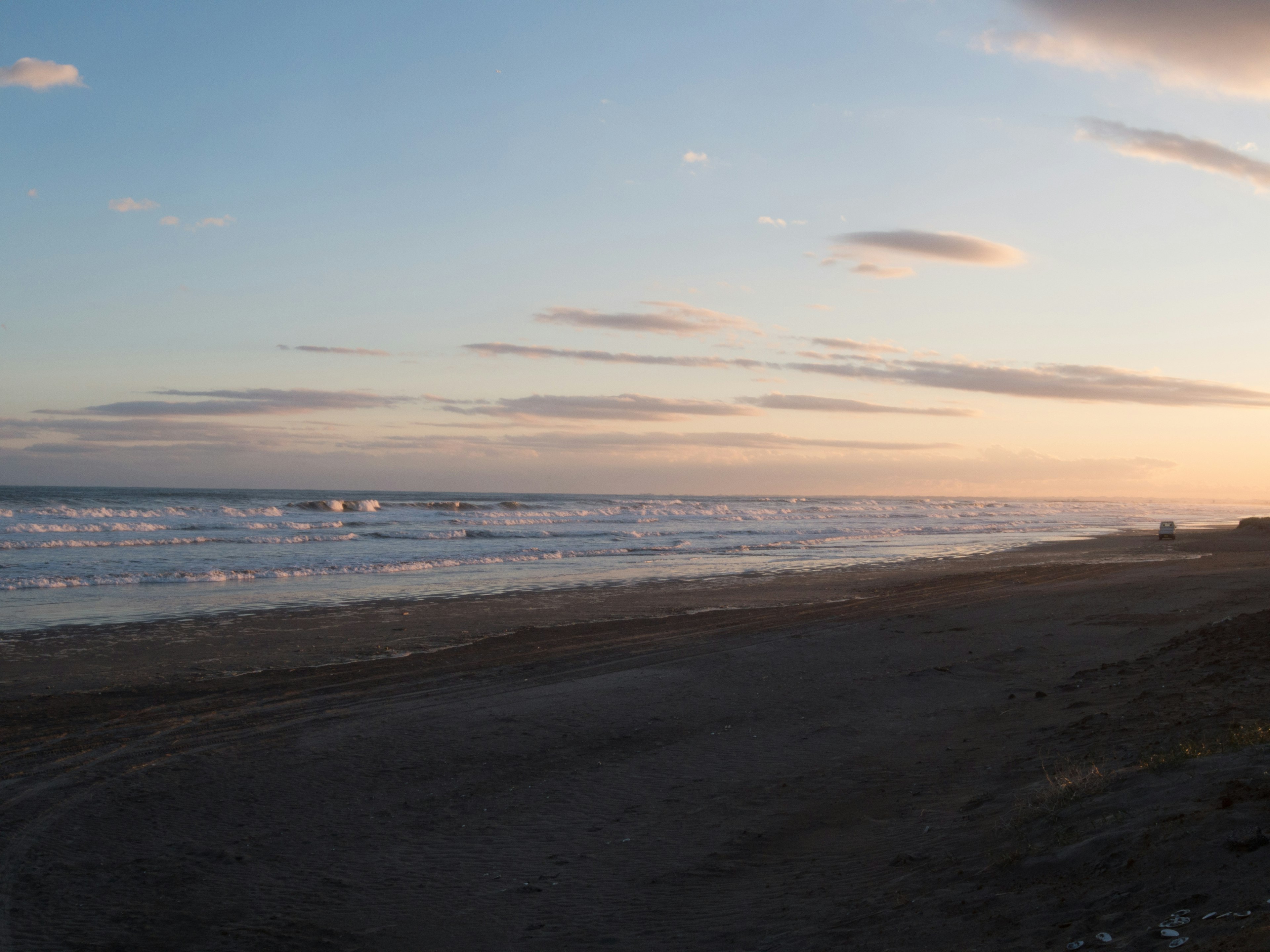 Küstenlandschaft bei Sonnenuntergang mit ruhigem Ozean und Sandstrand