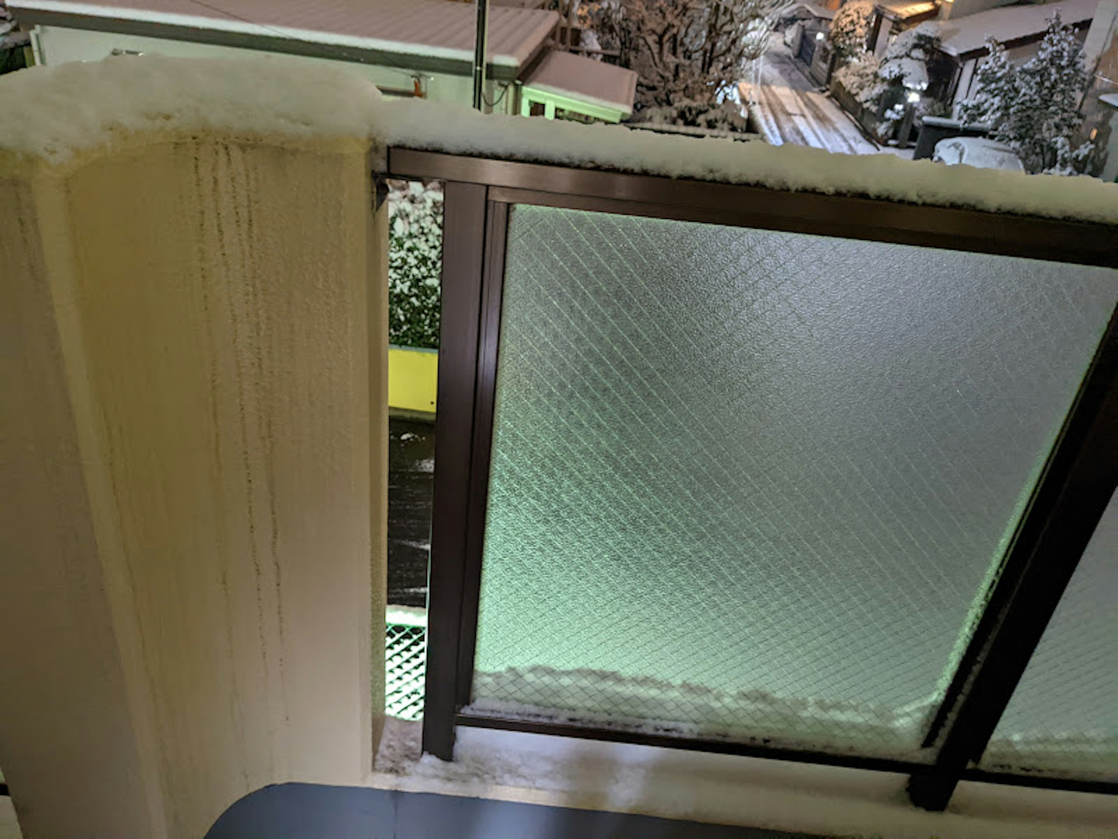 Snow-covered balcony railing and window view