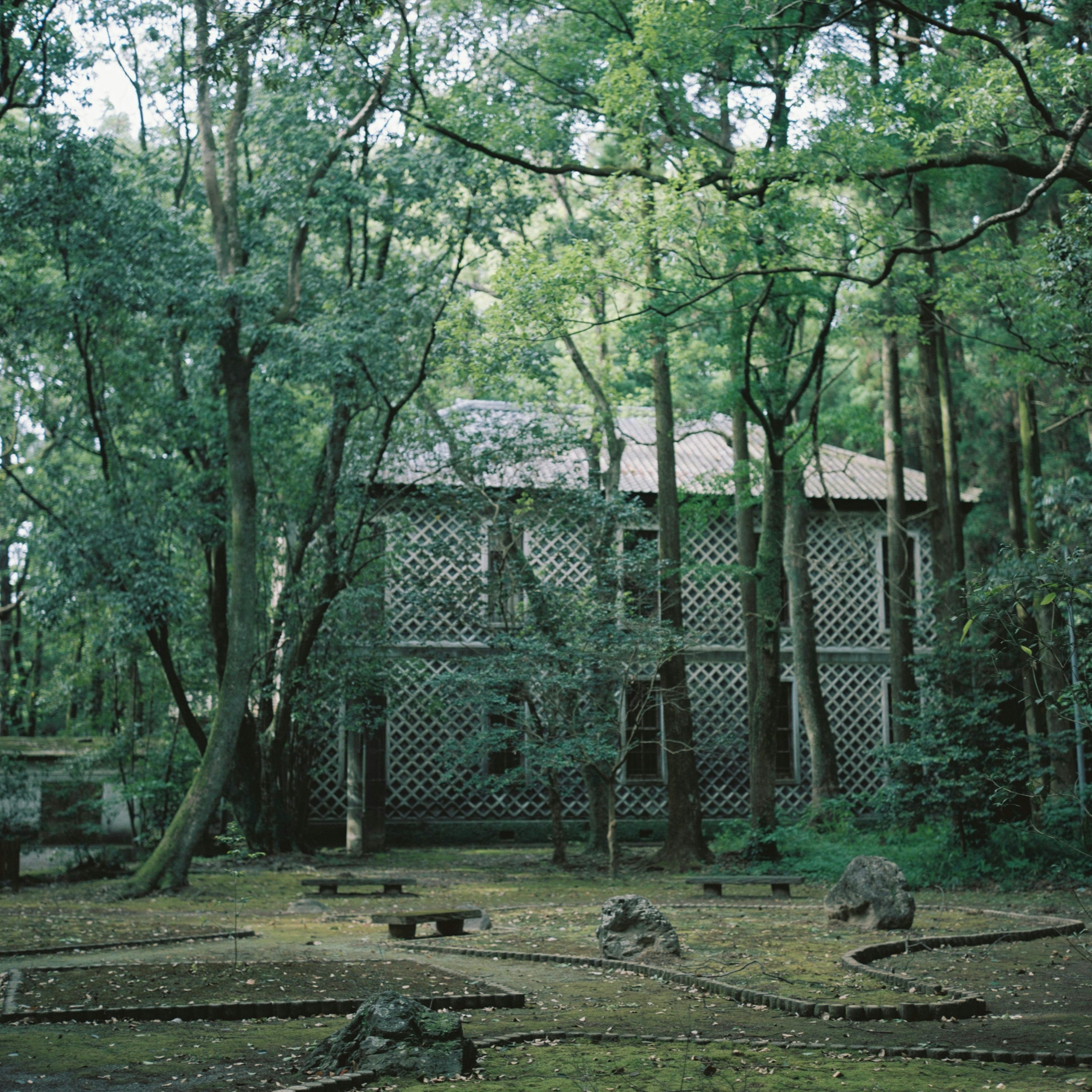 Un vecchio edificio a graticcio immerso in una foresta verdeggiante con un giardino di pietre