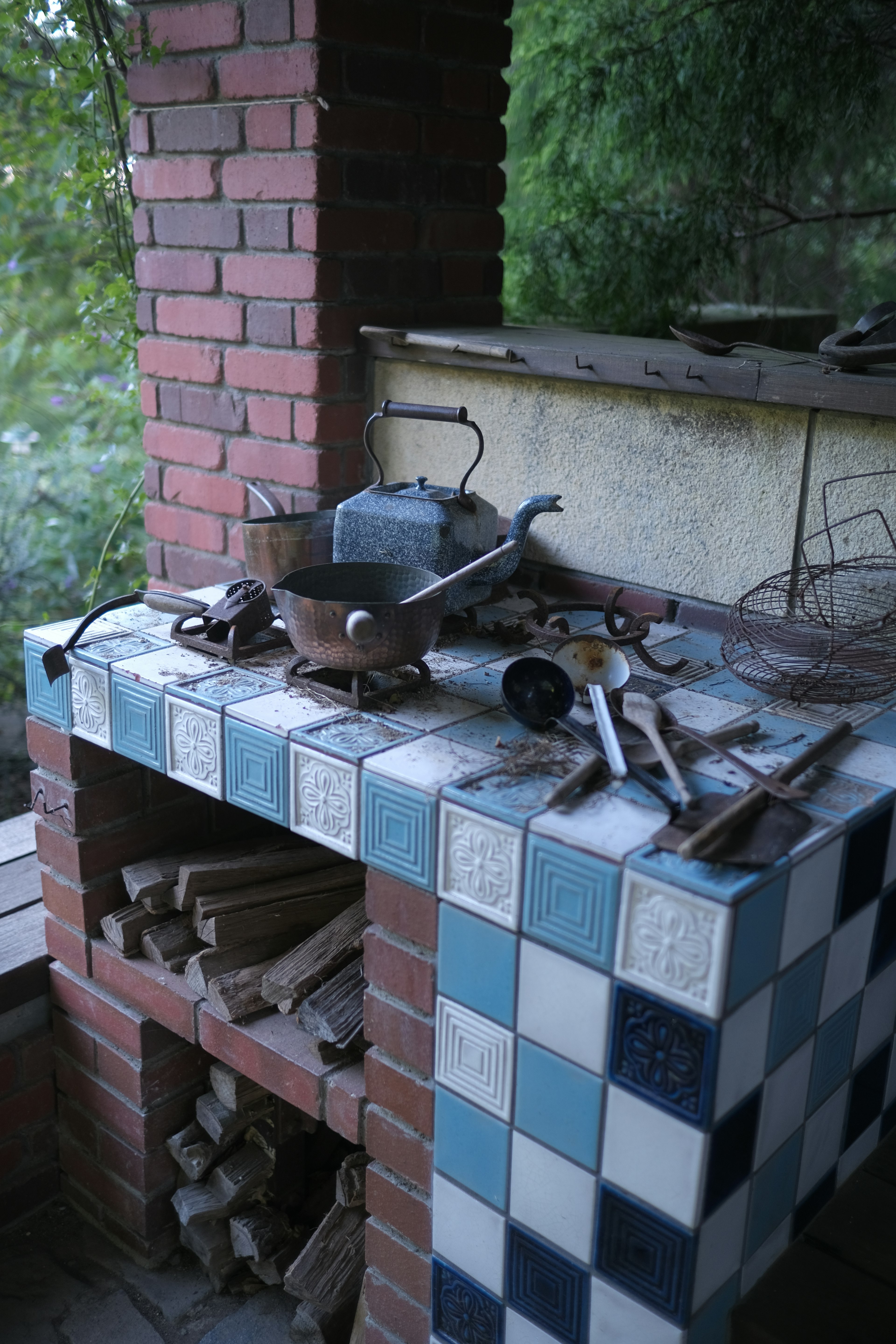 Ancien barbecue en brique avec des ustensiles de cuisine sur une table carrelée