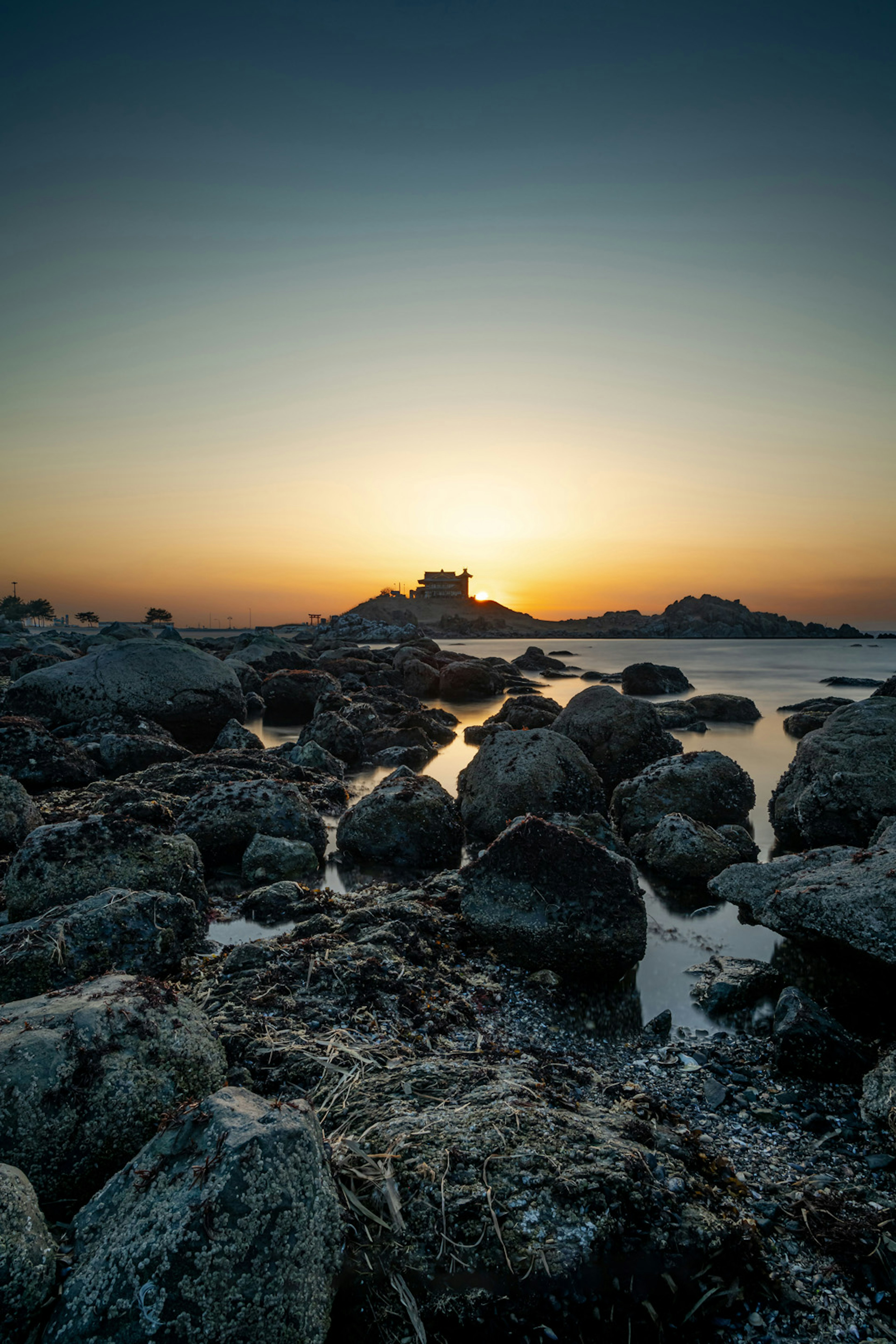 夕日が沈む海岸の岩場の風景