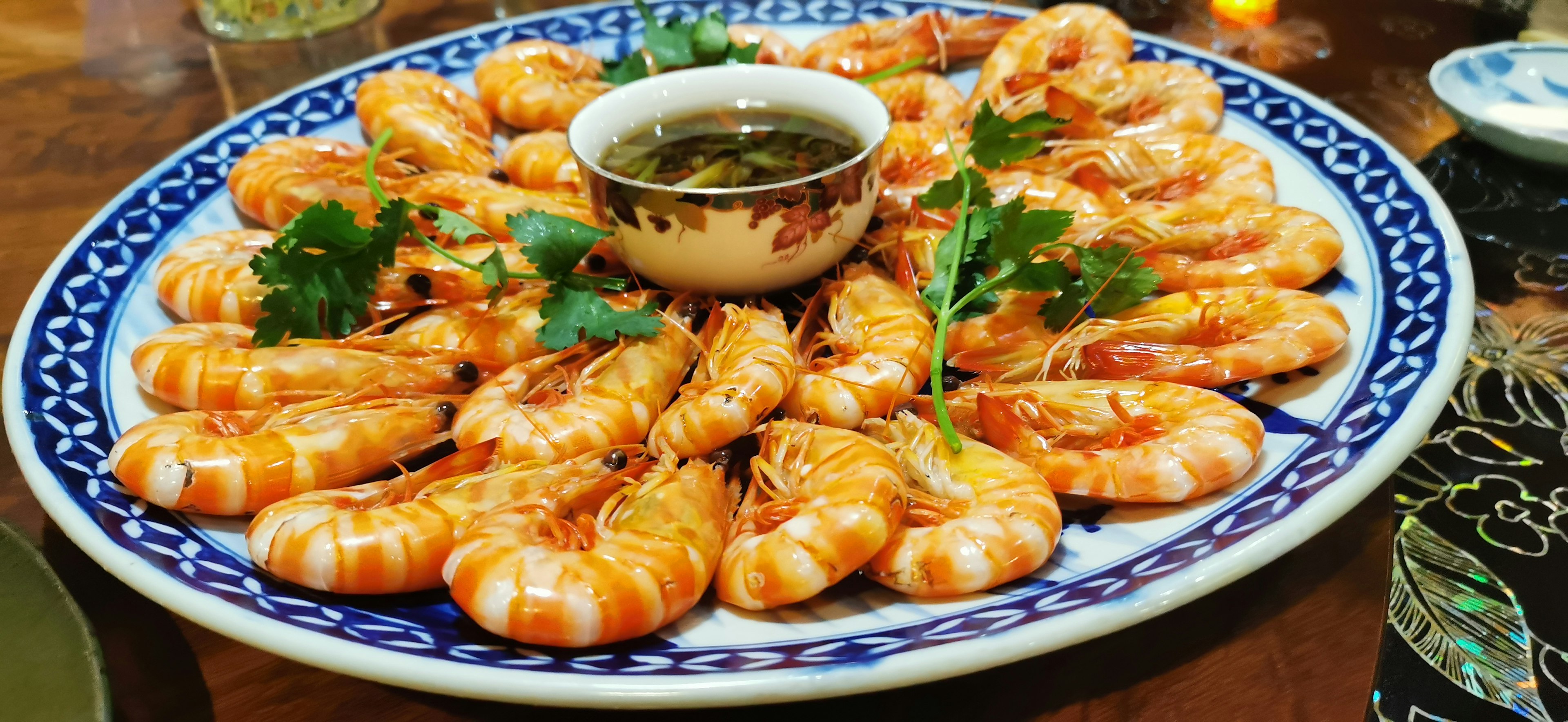 A beautiful platter of shrimp arranged elegantly with a small bowl of dipping sauce