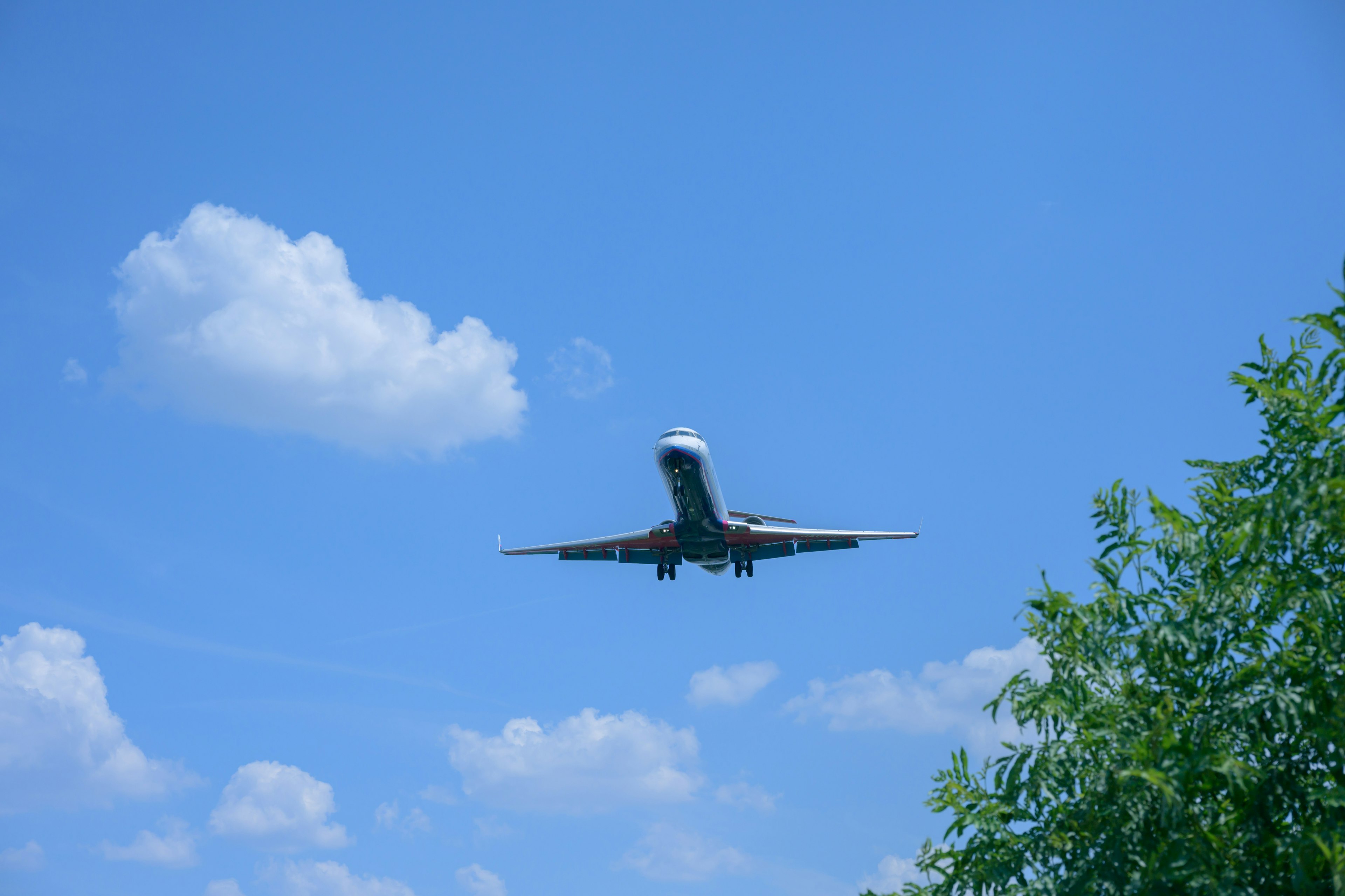 Un avión volando en un cielo azul claro con algunas nubes