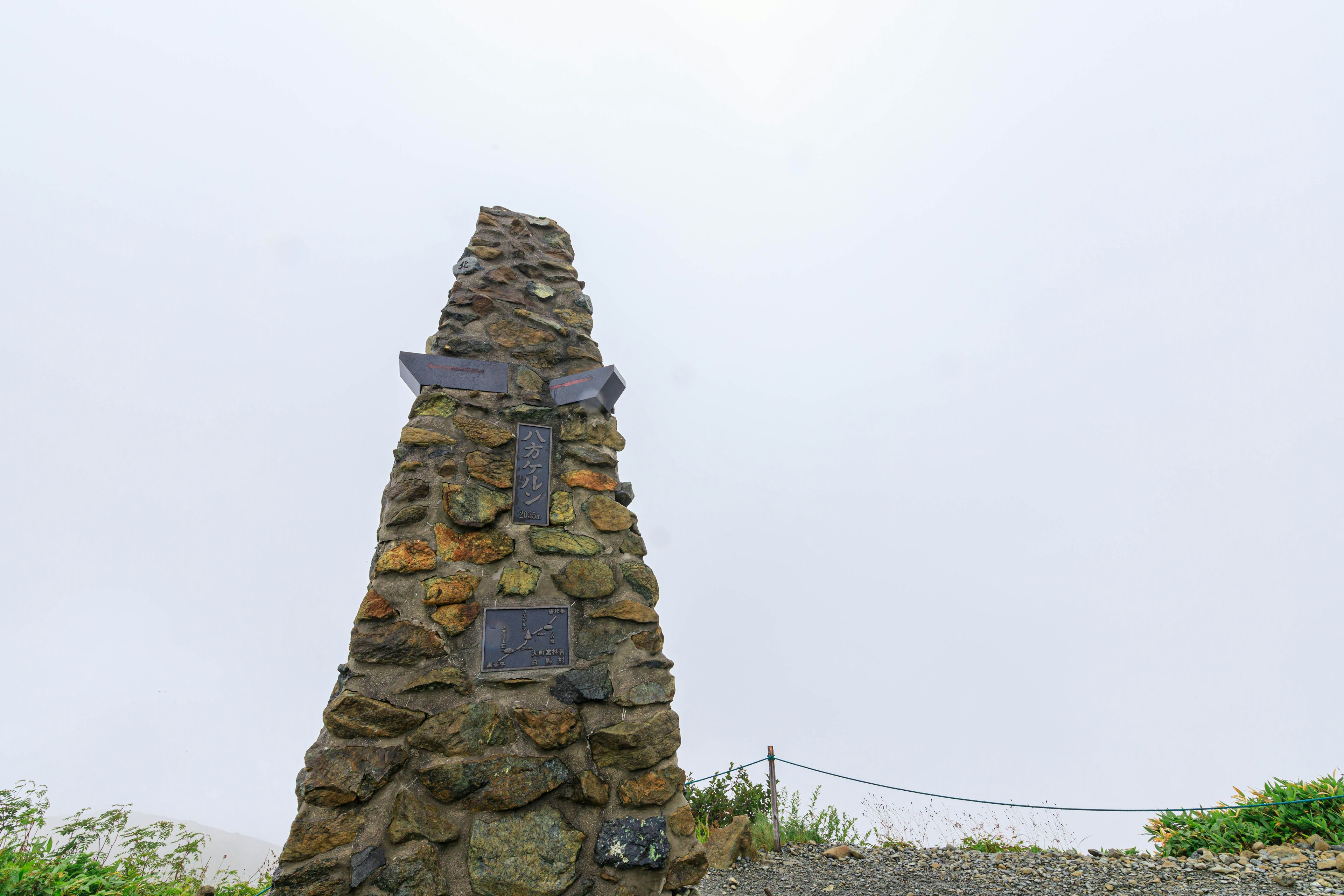 A stone monument standing in the fog with plaques