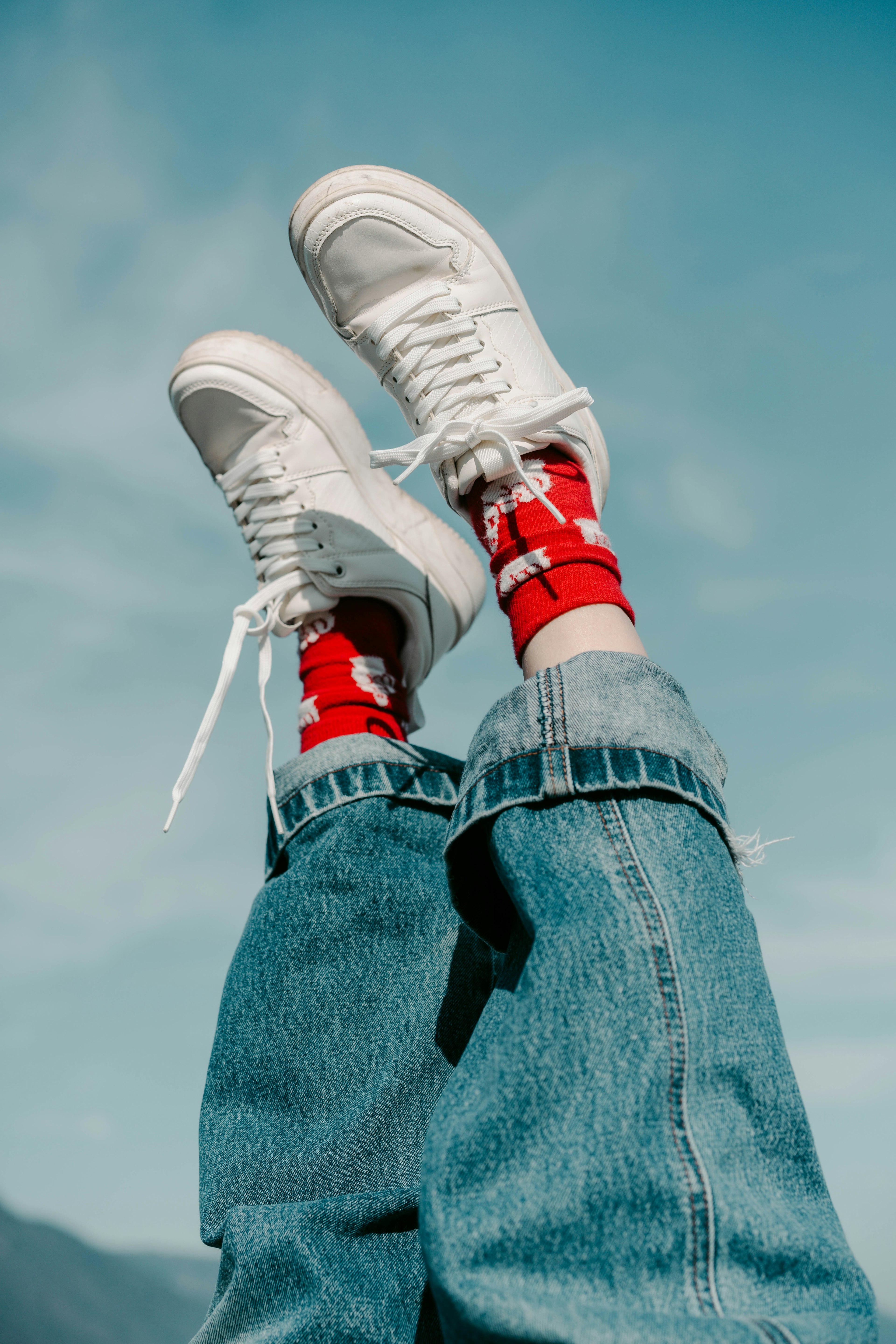 Kaki mengenakan sepatu putih dan kaus kaki merah dengan latar belakang langit biru