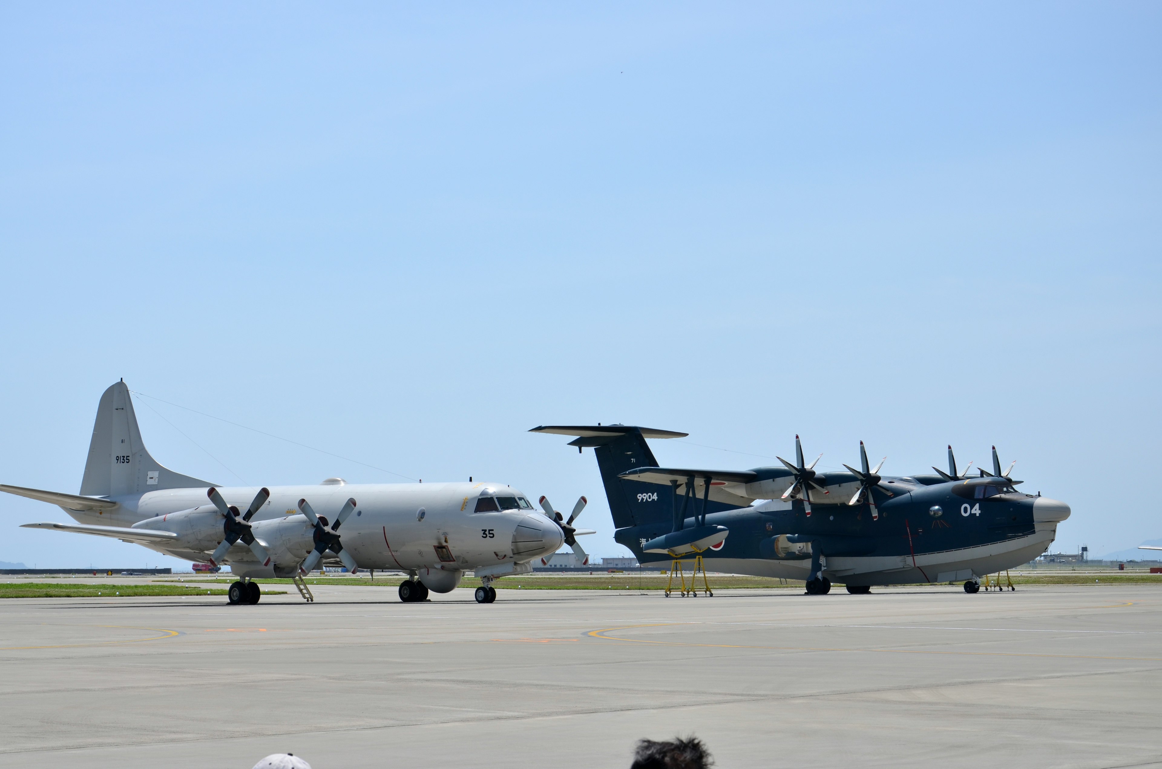 White aircraft and blue aircraft on an airport runway