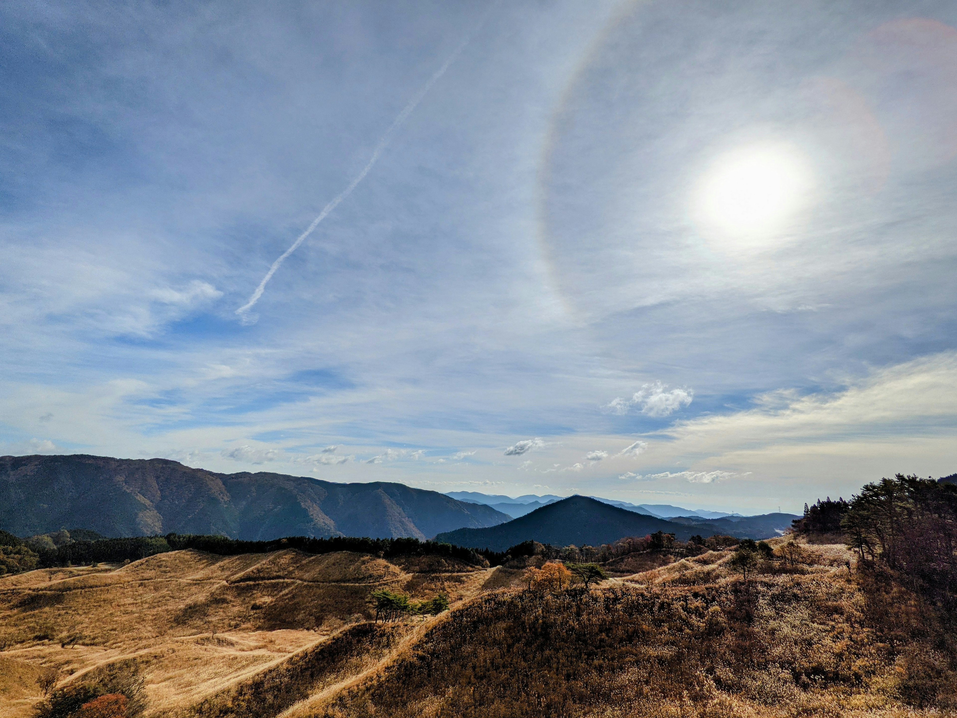 Cielo despejado con montañas y un halo arcoíris alrededor del sol