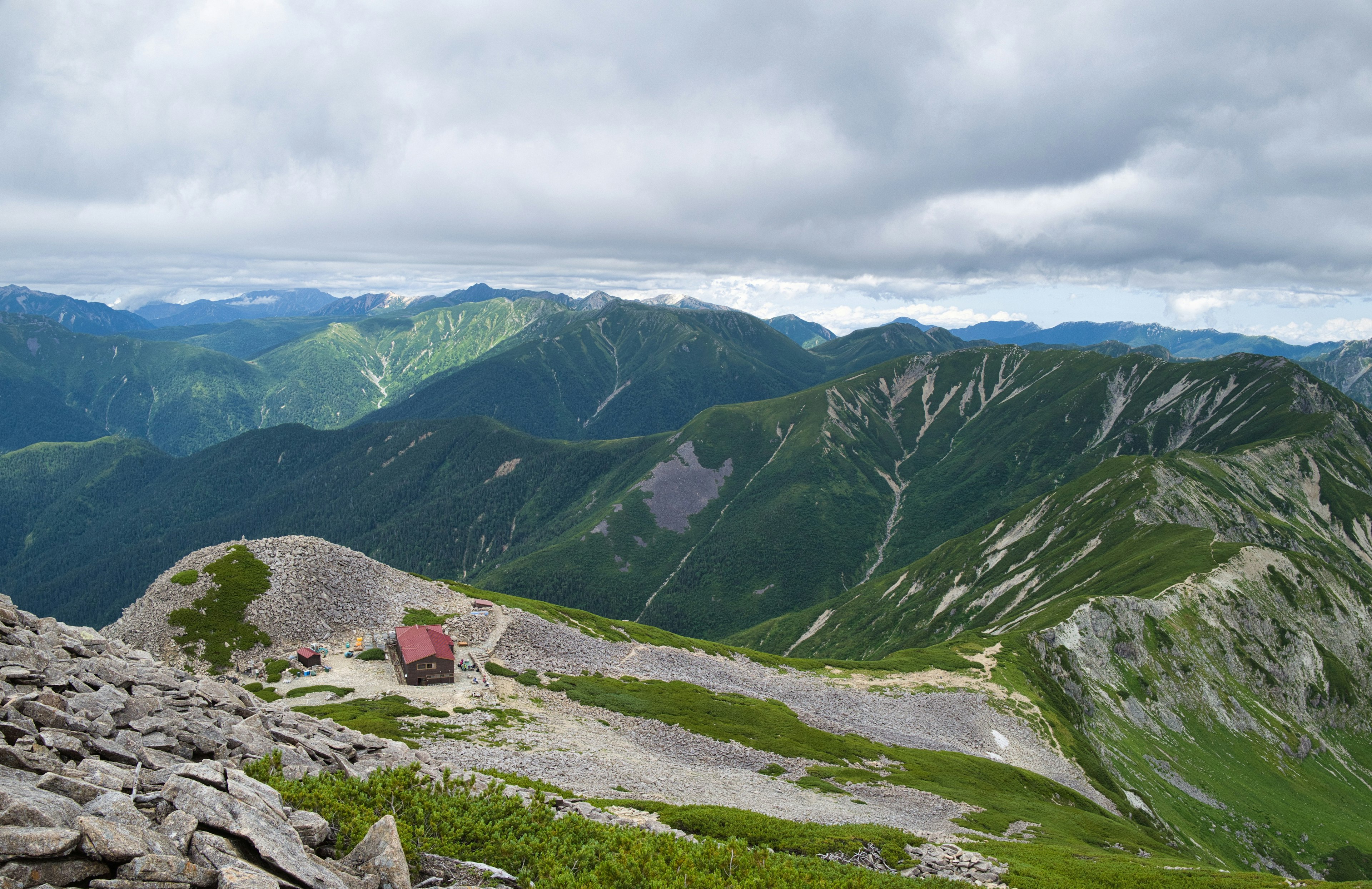 Vista panoramica delle montagne con una piccola cabina rossa