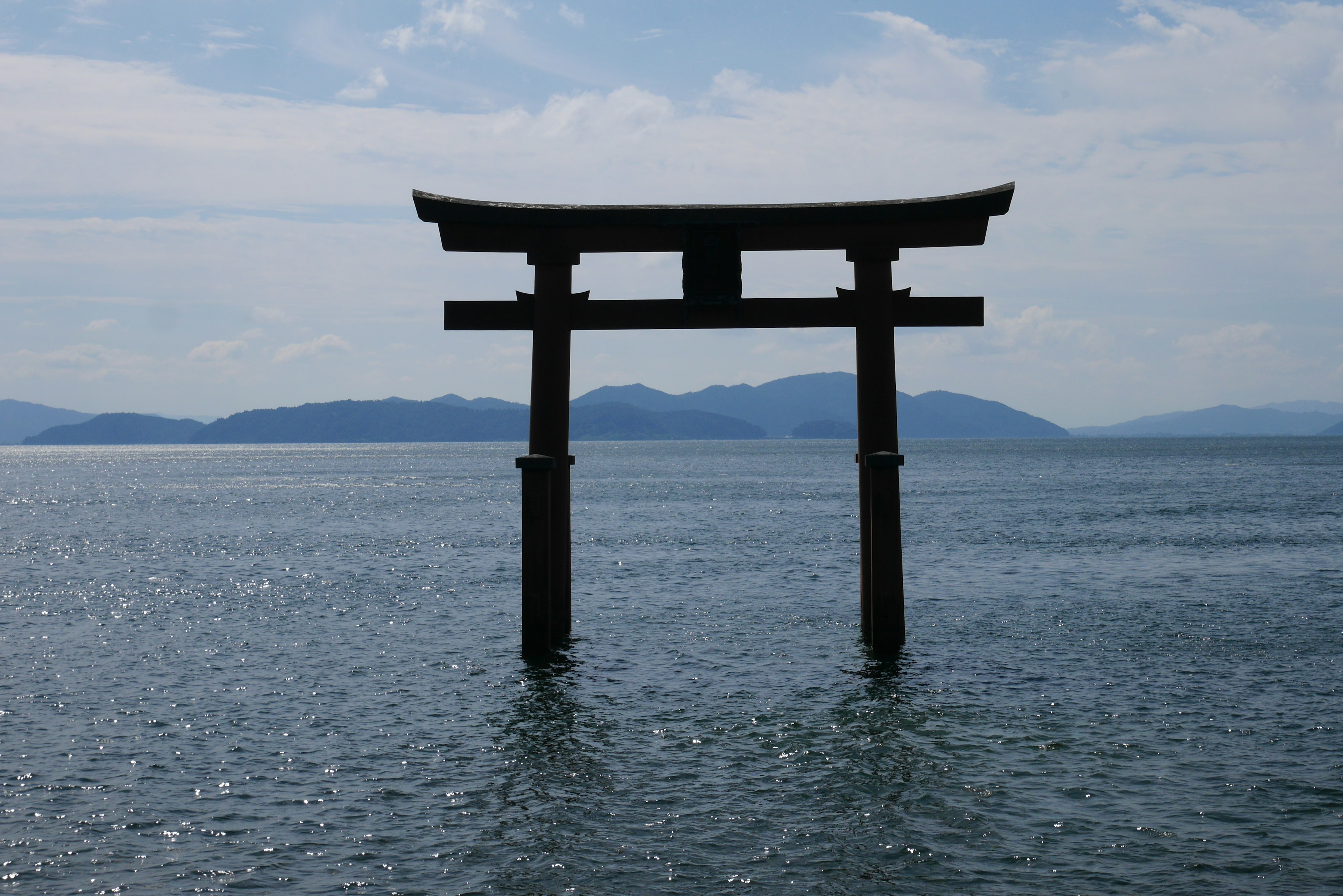 水面に立つ鳥居と山々の背景