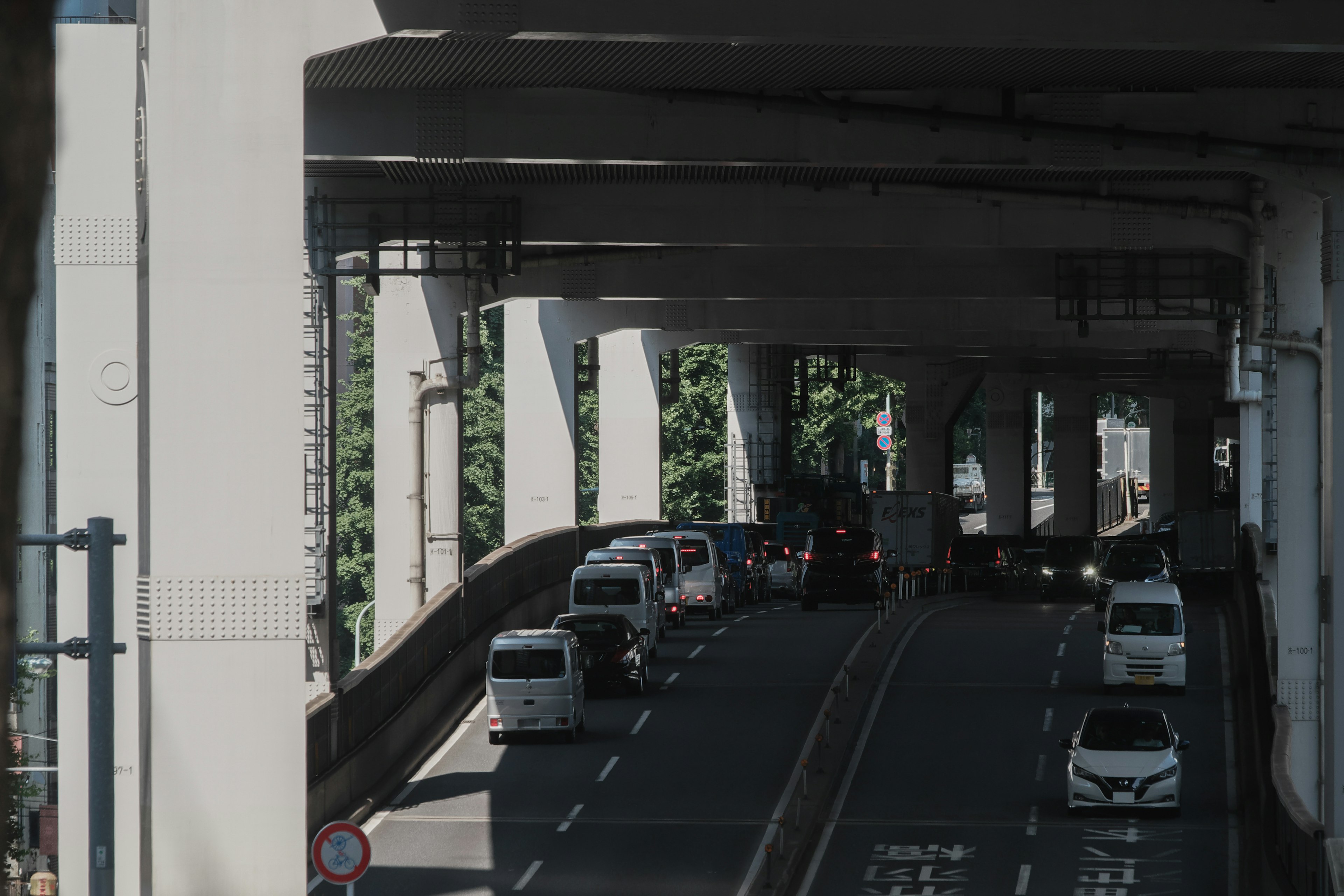 Vista de vehículos en una carretera elevada con pilares de soporte