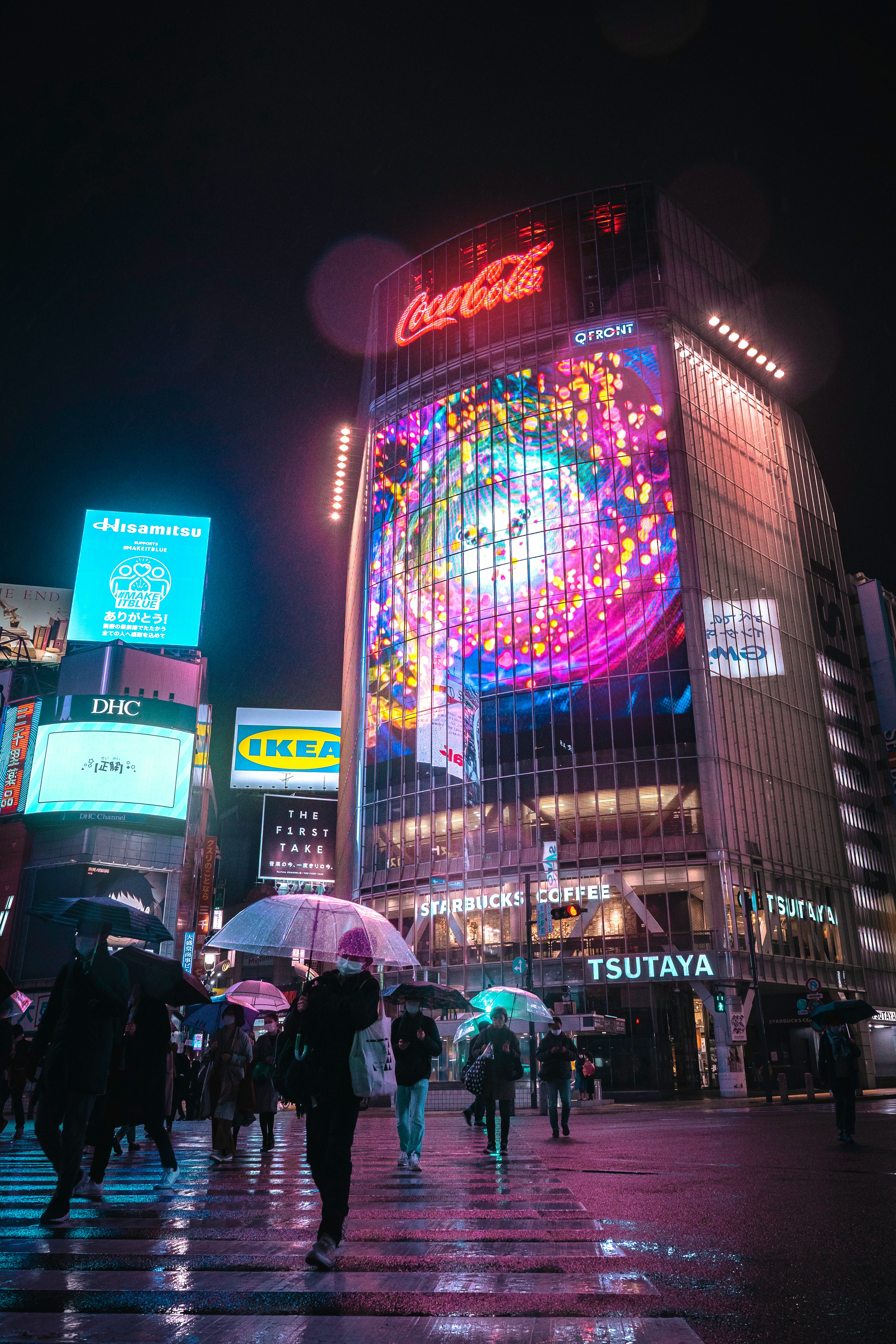 Leuchtendes Coca-Cola-Schild und bunte Werbung in Shibuya bei Nacht