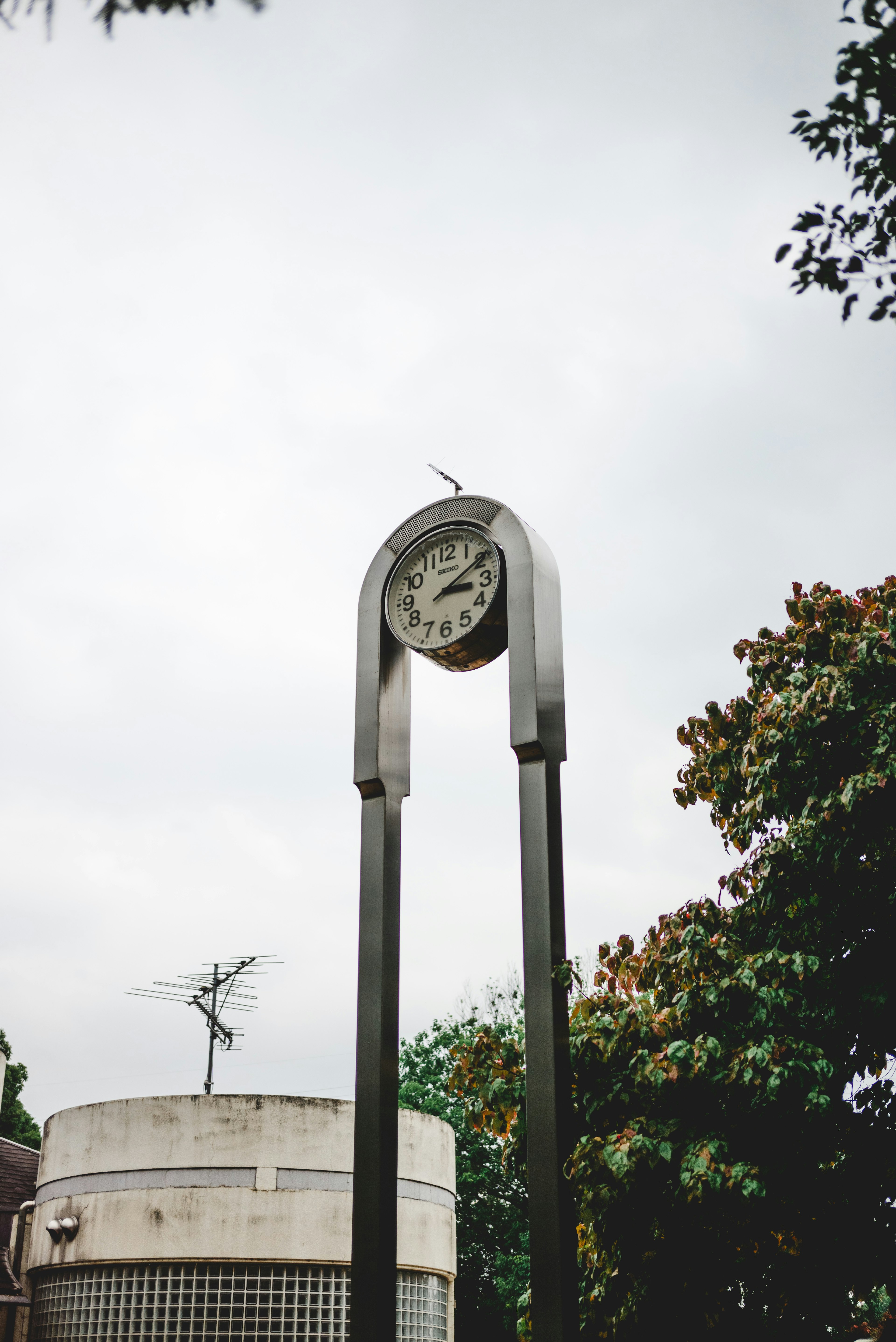 公園の中のユニークなデザインの時計と木々の風景