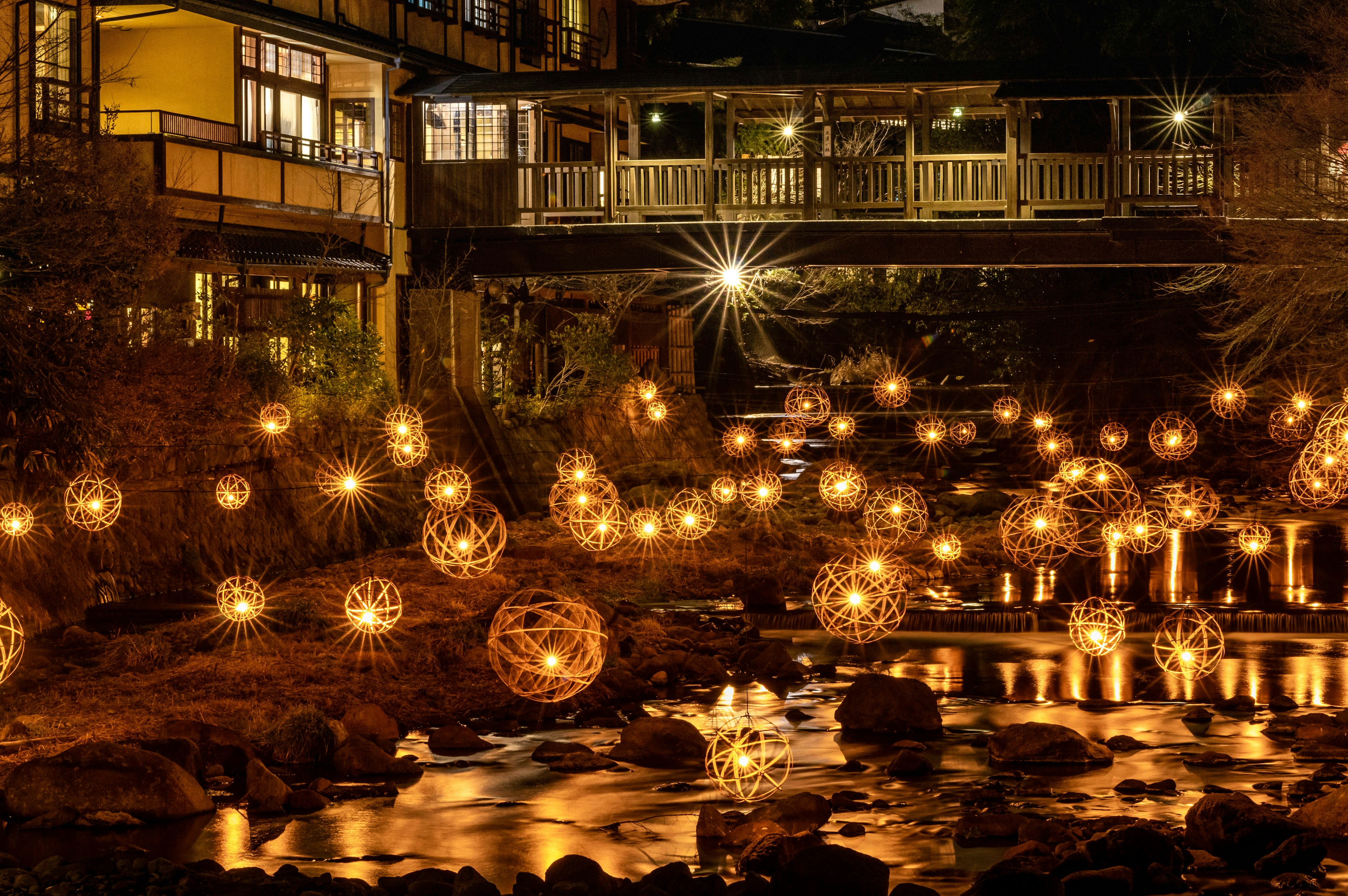 Vista panoramica di lanterne luminose che galleggiano su un fiume di notte con un ponte