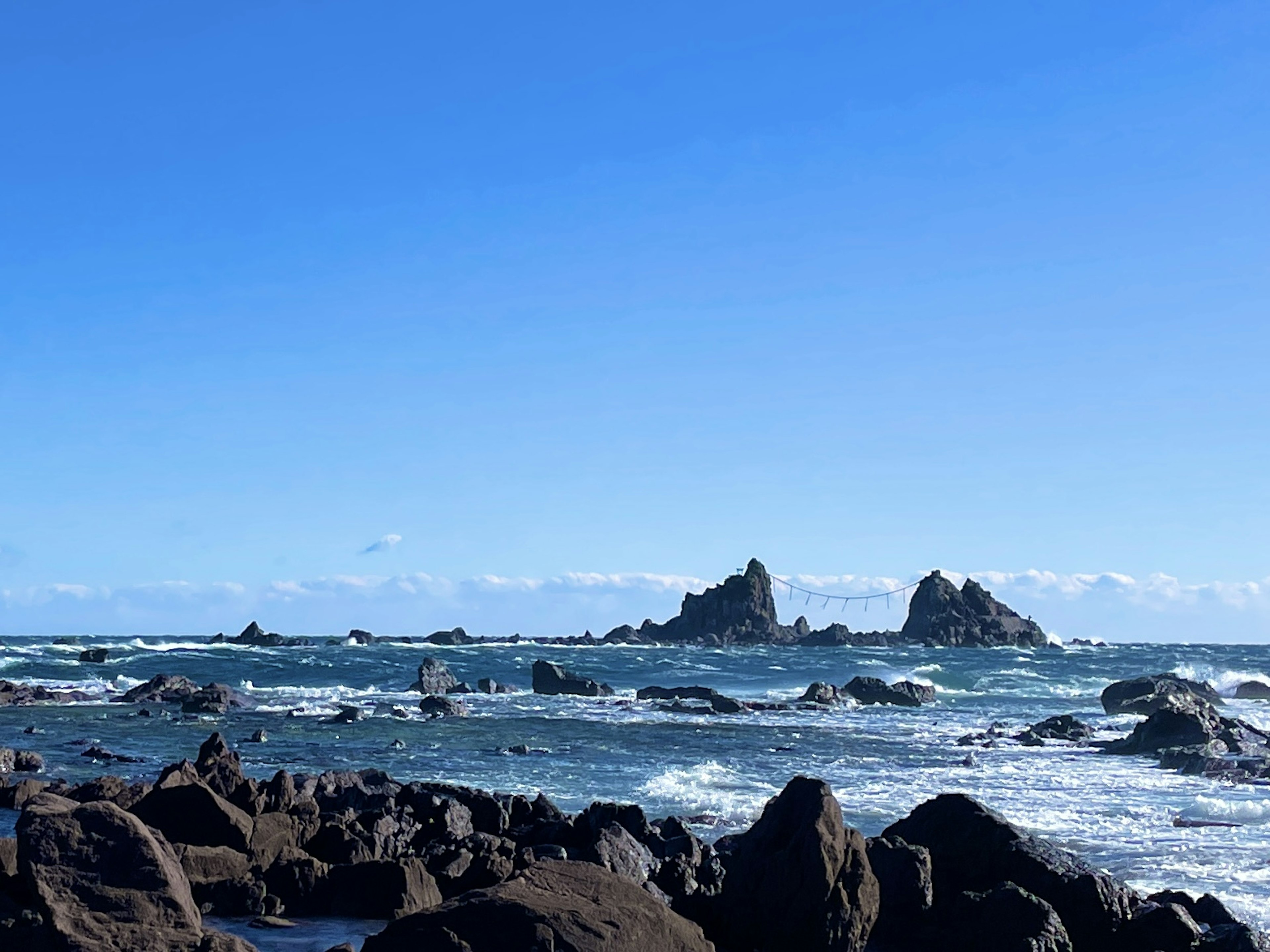 Paysage avec des îles rocheuses entourées d'un ciel bleu et des vagues océaniques