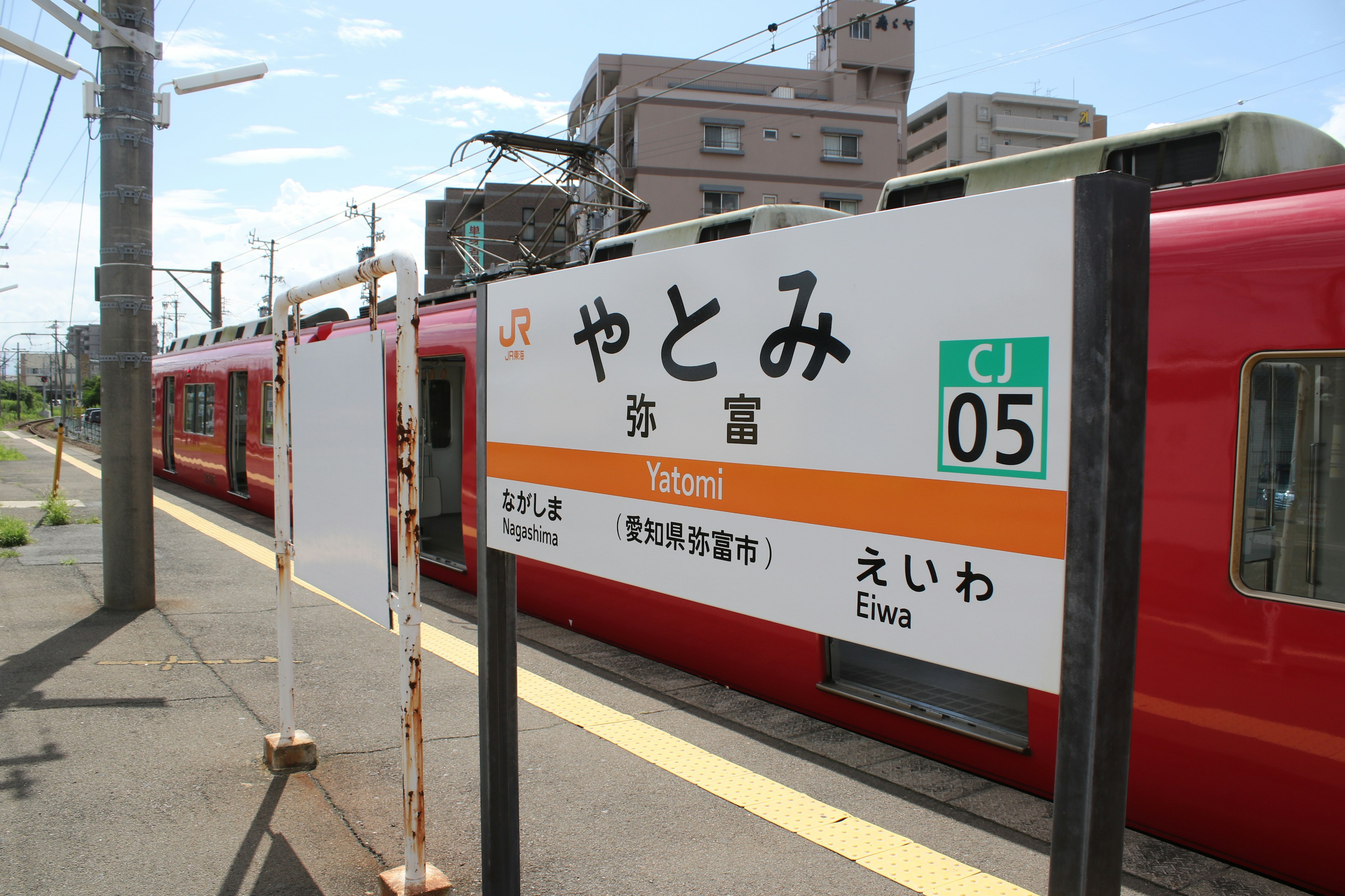 赤い電車が停車しているやとみ駅の看板