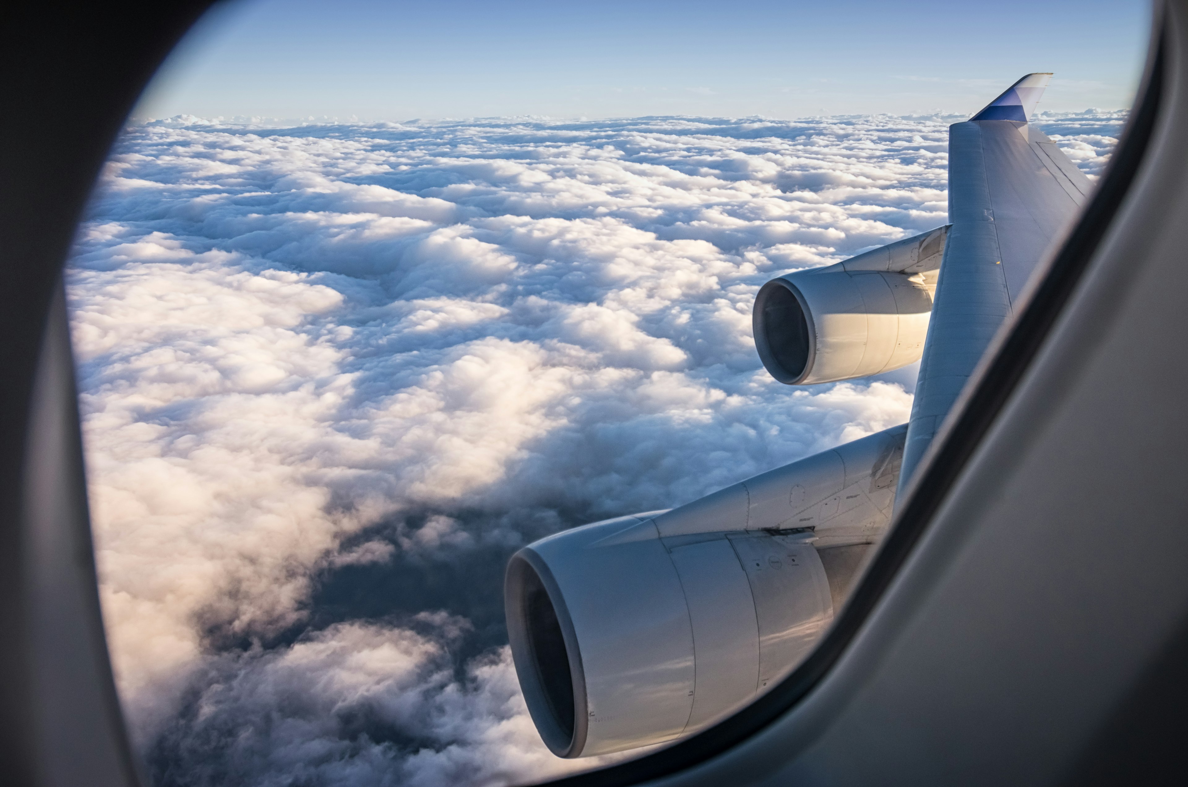 飛行機の窓からの雲の上の景色とエンジン