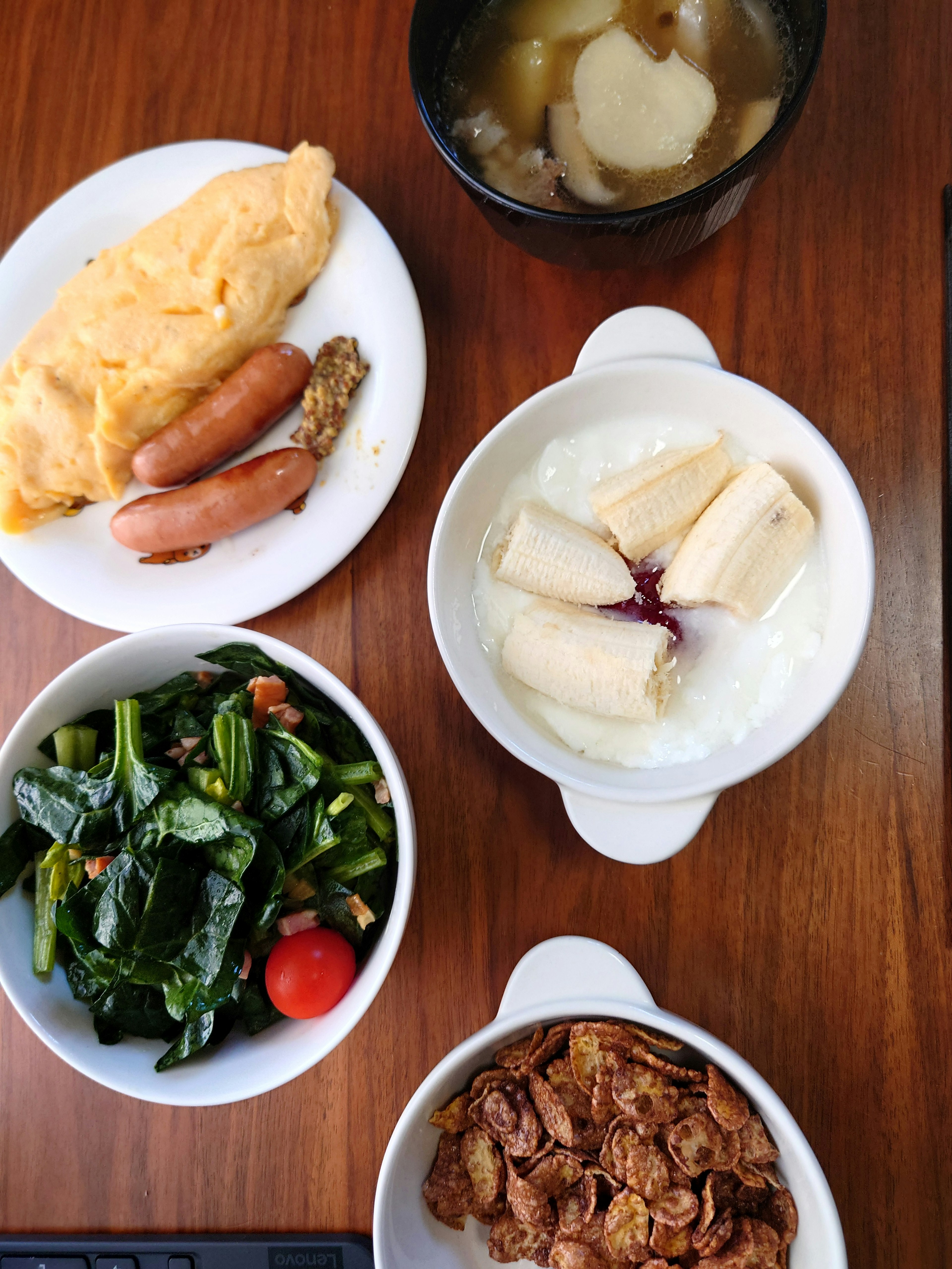 Assiette de petit déjeuner avec des œufs brouillés des saucisses de la salade du yaourt et de la soupe