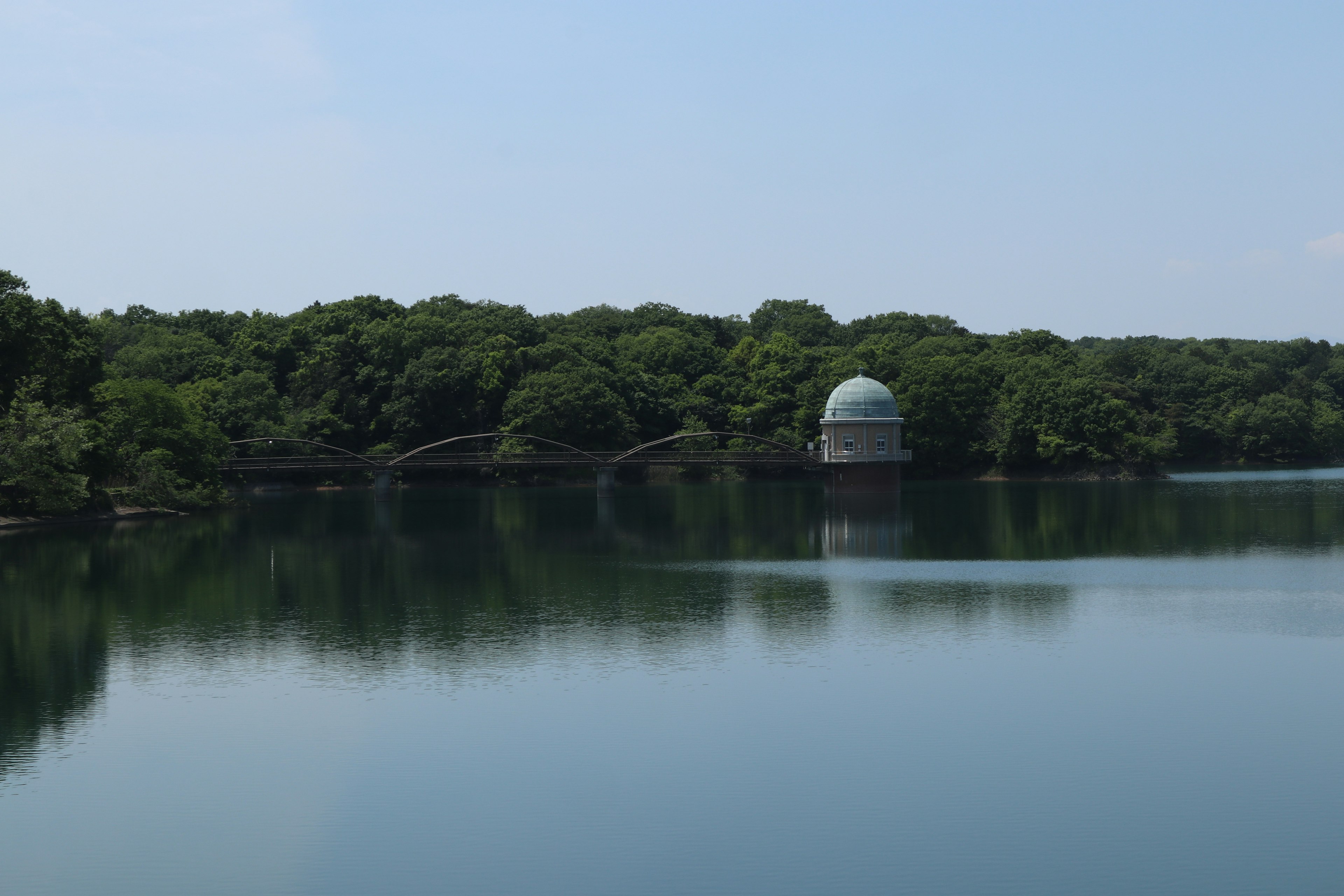 Vista escénica de un lago tranquilo rodeado de vegetación exuberante con un edificio en forma de cúpula