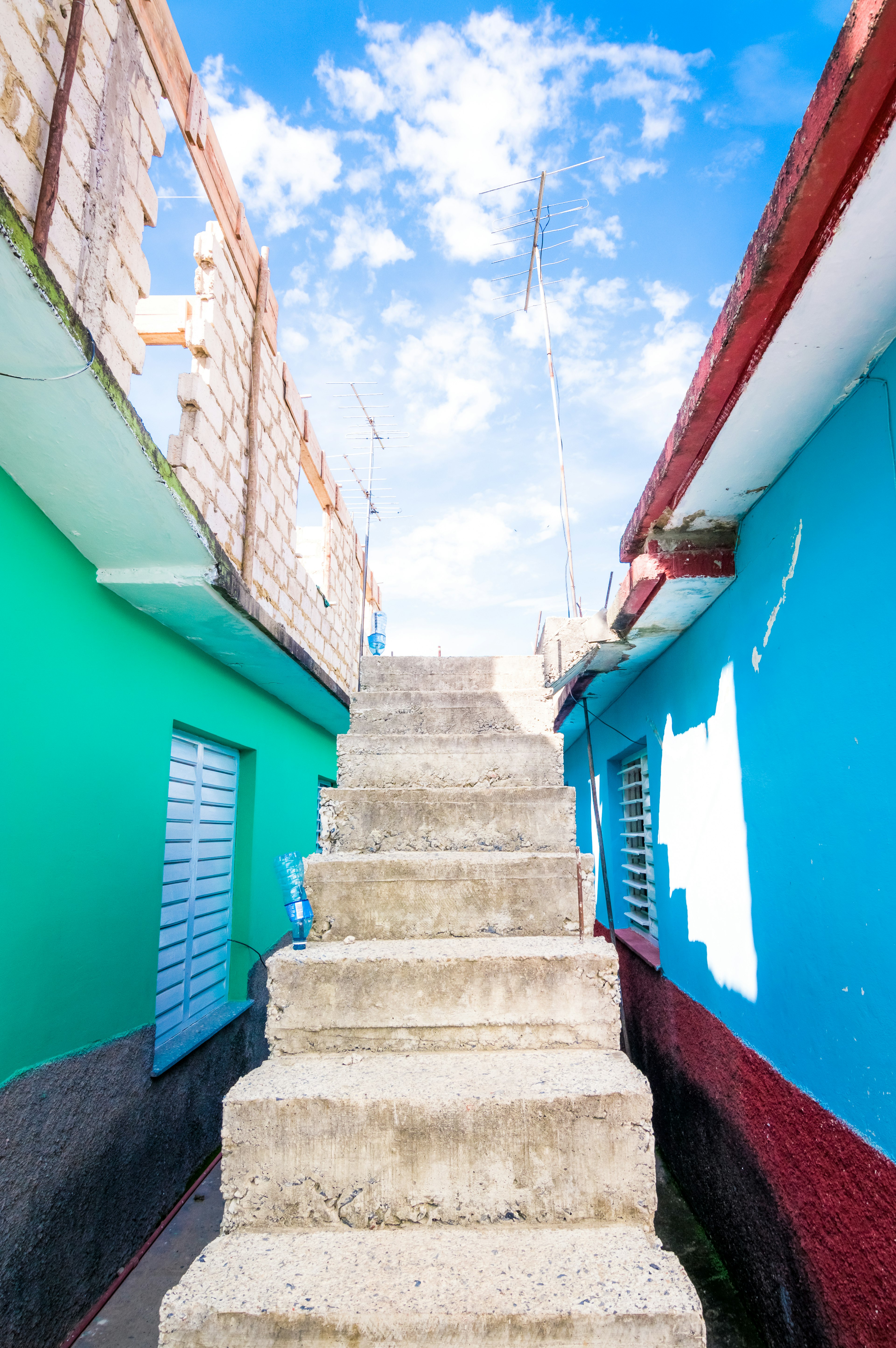 Escalier en pierre menant vers le haut entre des murs colorés sous un ciel lumineux