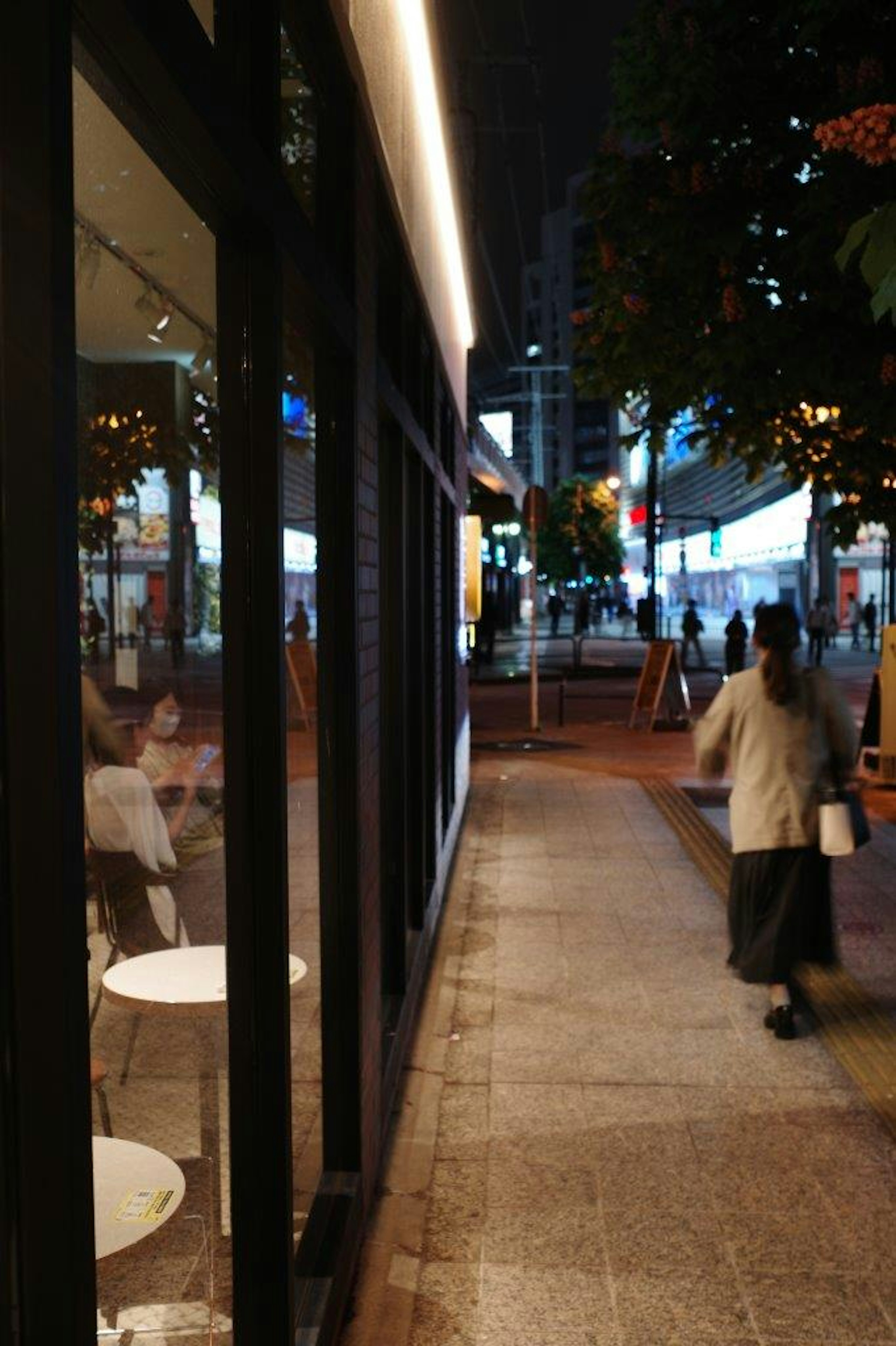 Scène urbaine nocturne avec l'extérieur d'un café illuminé et des piétons marchant