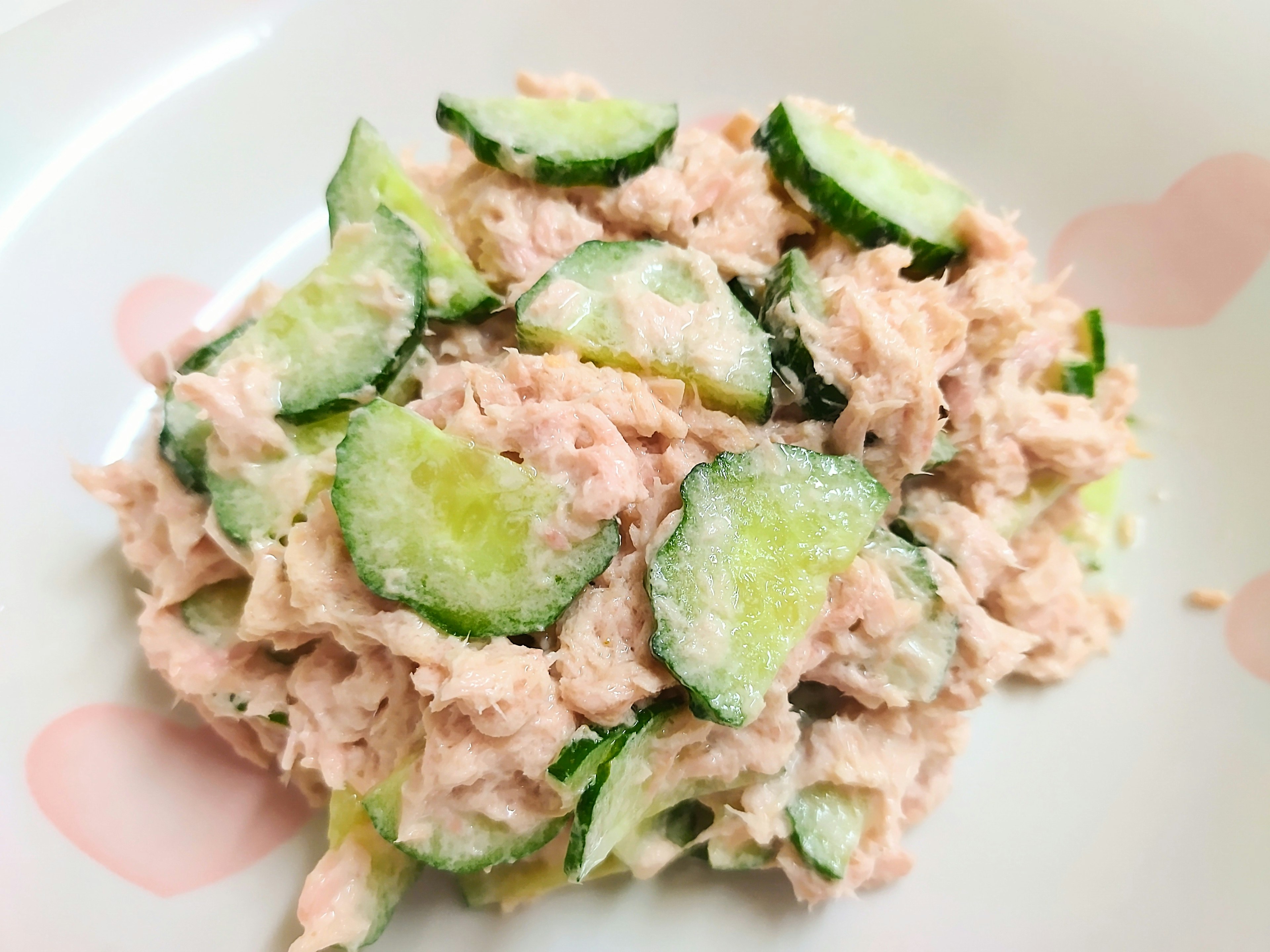 Un plato de ensalada de atún mezclada con rodajas de pepino