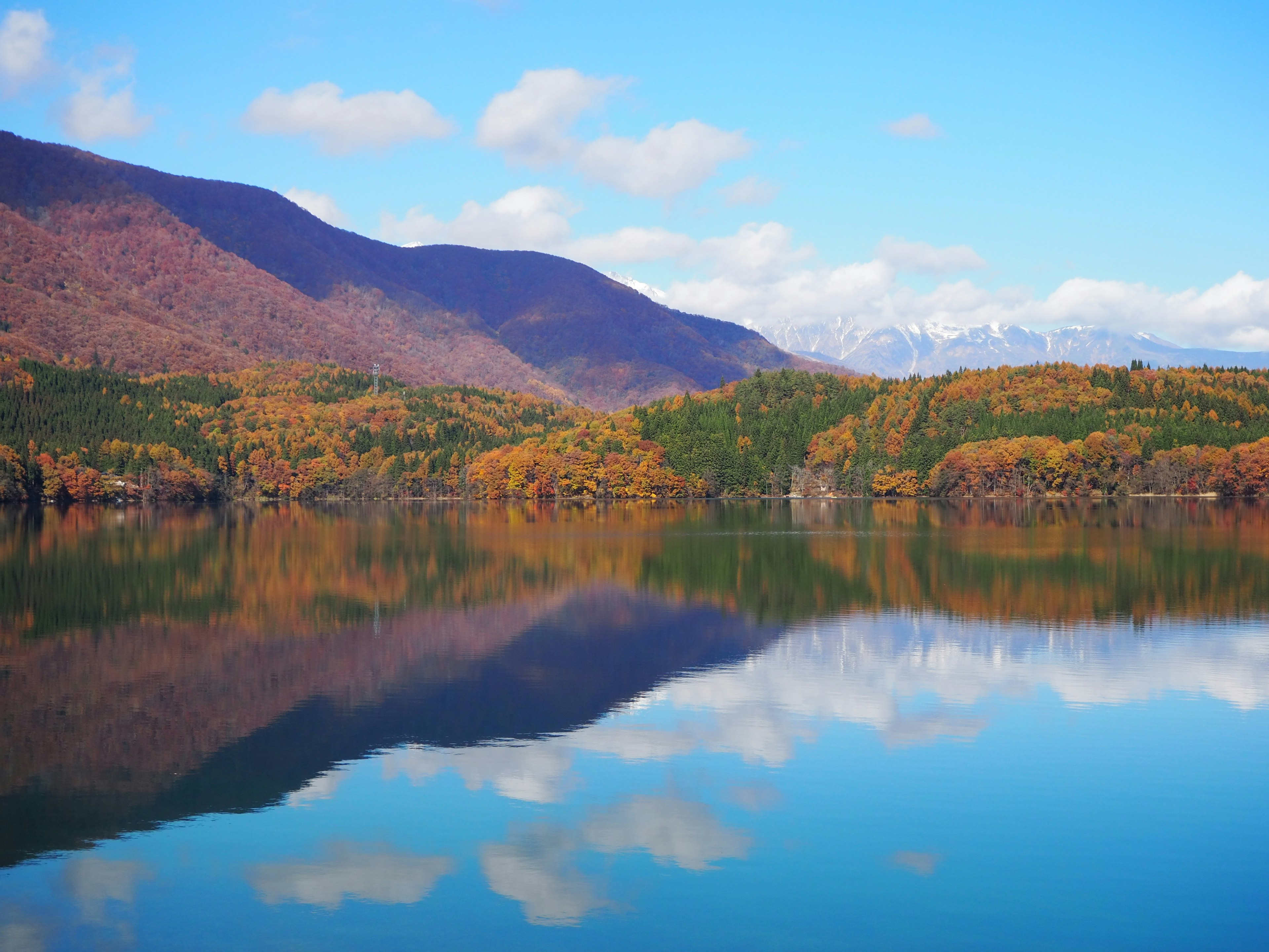 Vista escénica de un lago que refleja árboles de otoño coloridos y montañas