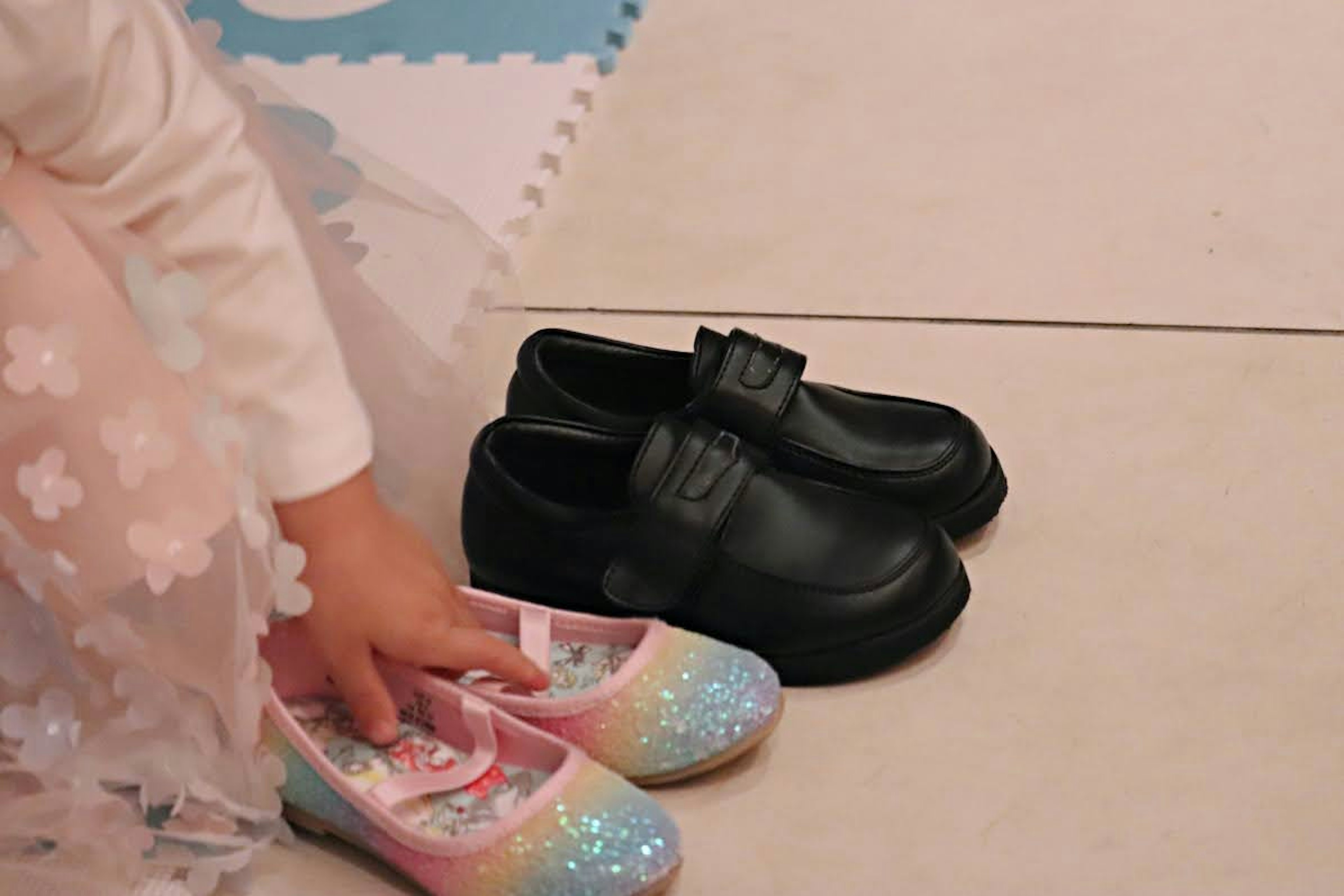 Child holding colorful shoes and black shoes