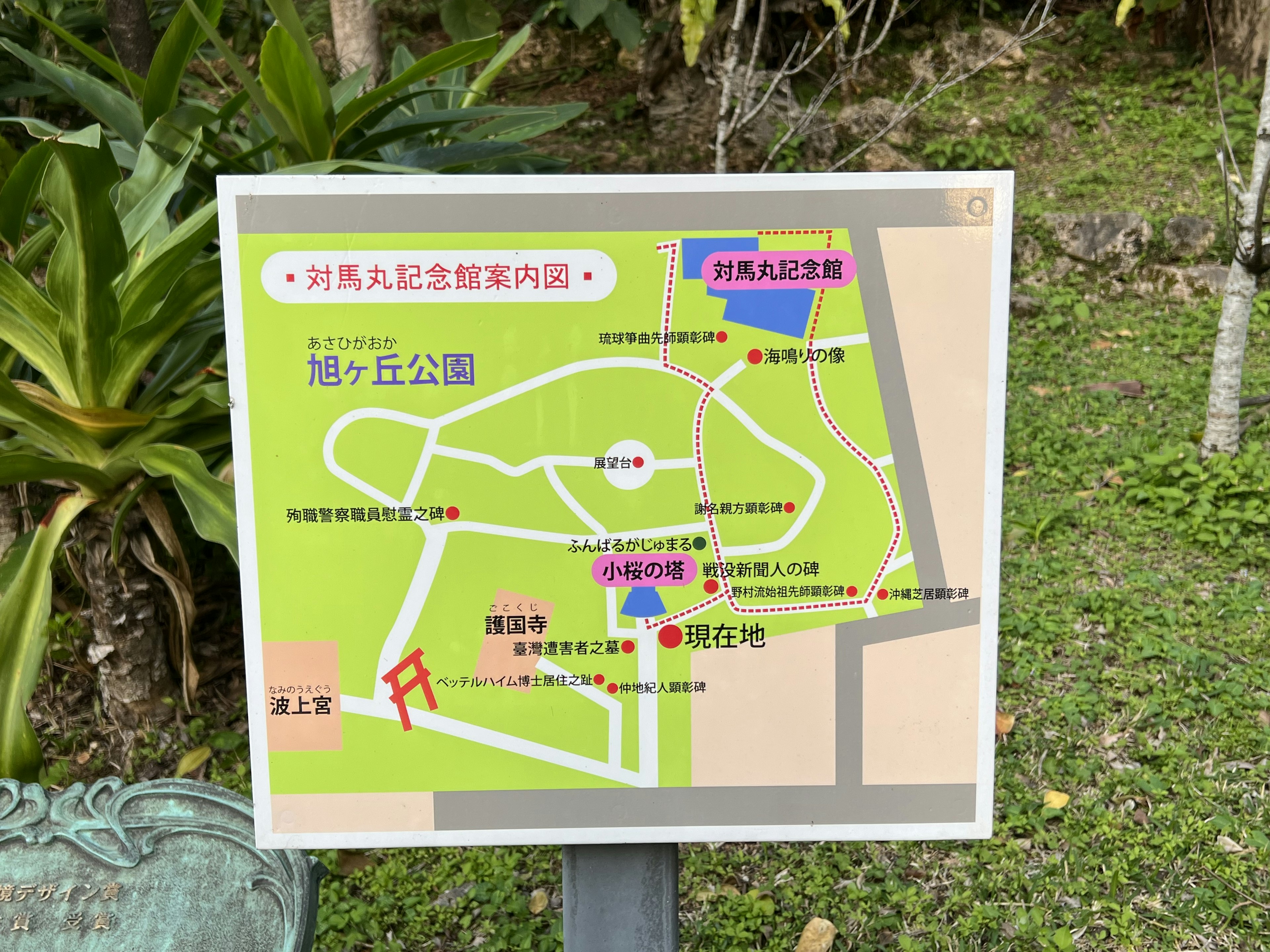 公園の地図を示す看板 緑色の背景に白い文字と赤いシンボル