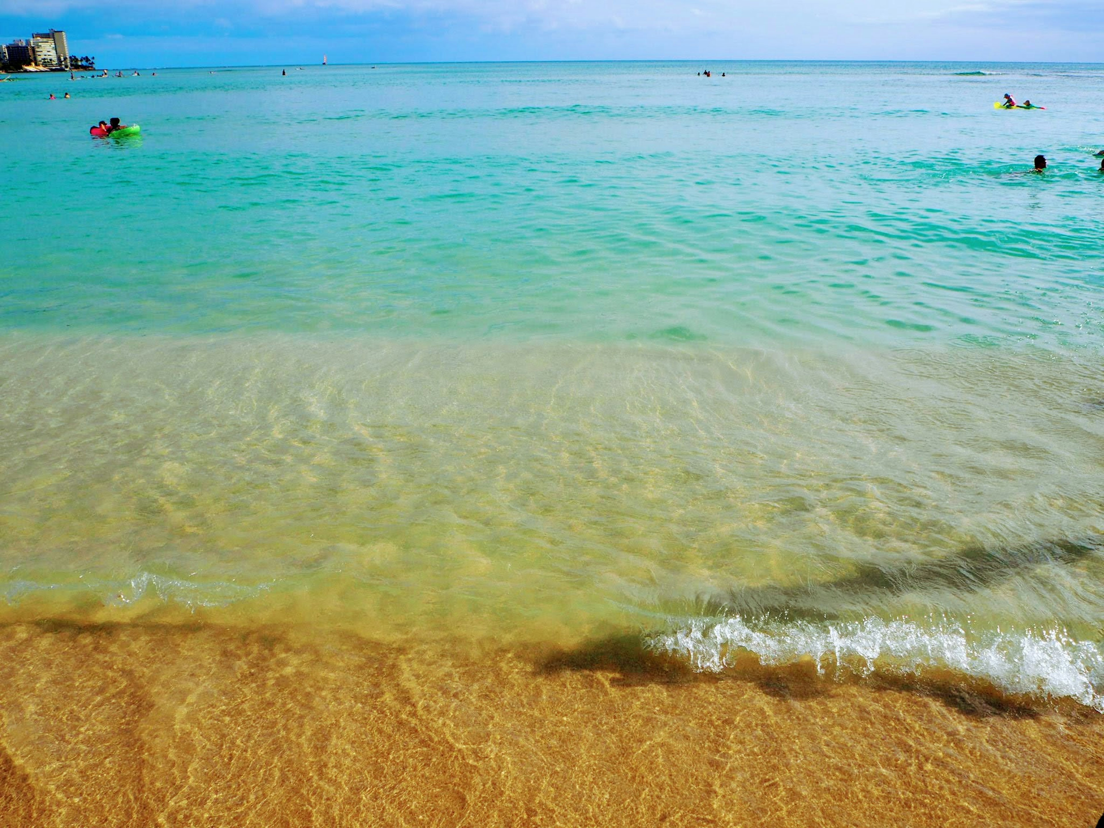 Szenische Ansicht des blauen Ozeans und des Sandstrandes mit schwimmenden Menschen