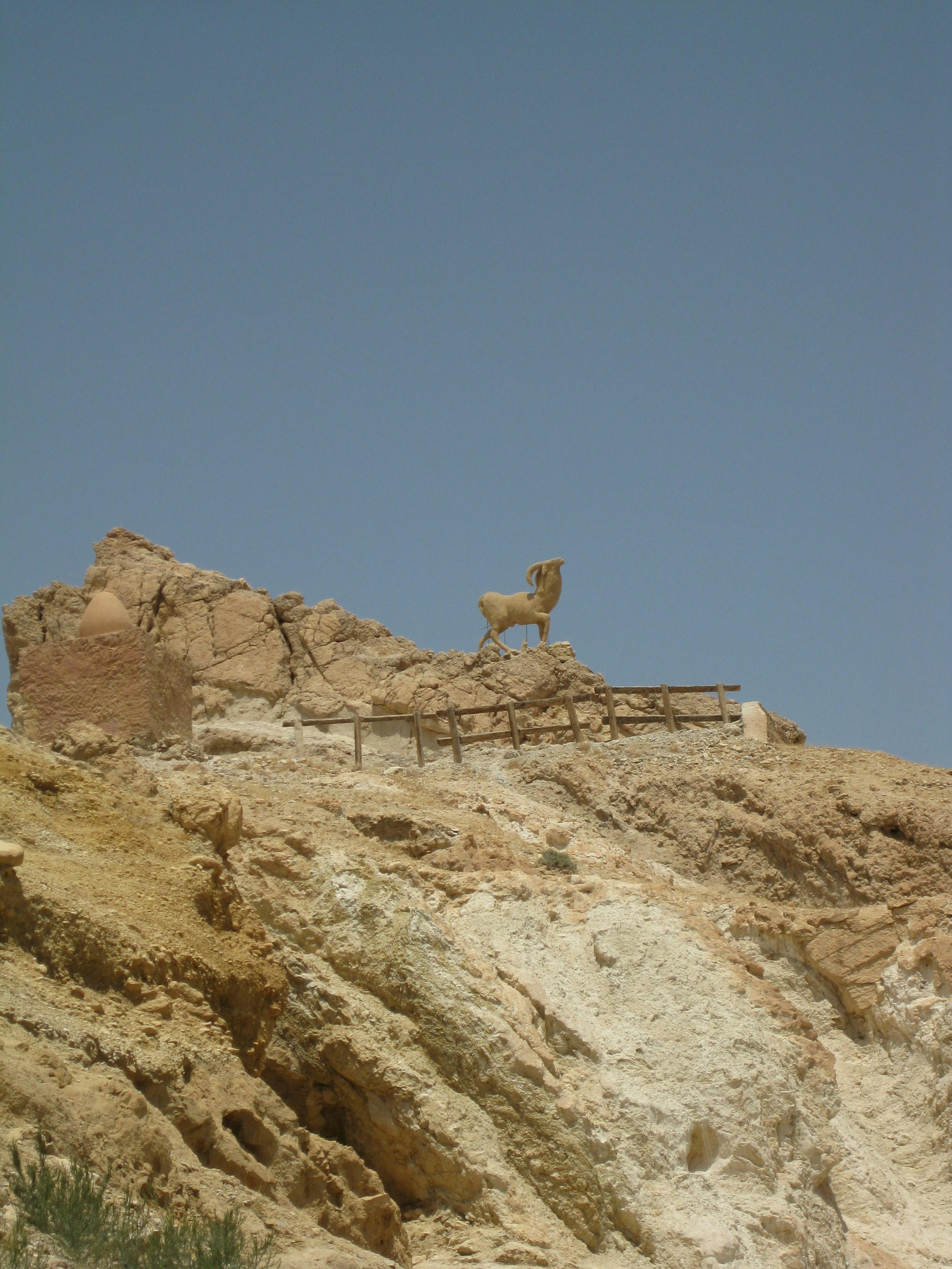 Une statue de cheval se tenant sur un rocher sous un ciel bleu clair