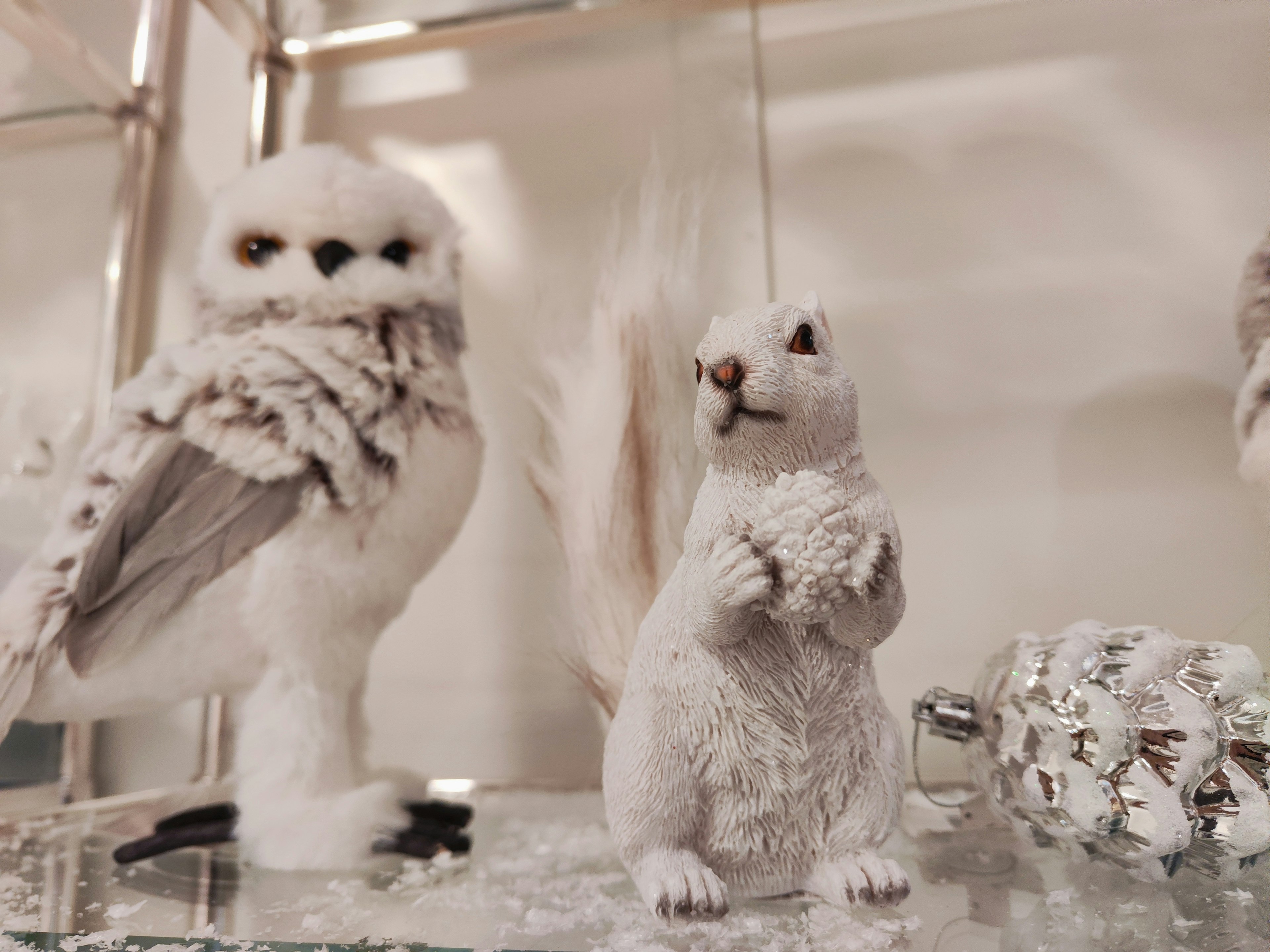 Display featuring a white owl and a white squirrel decoration